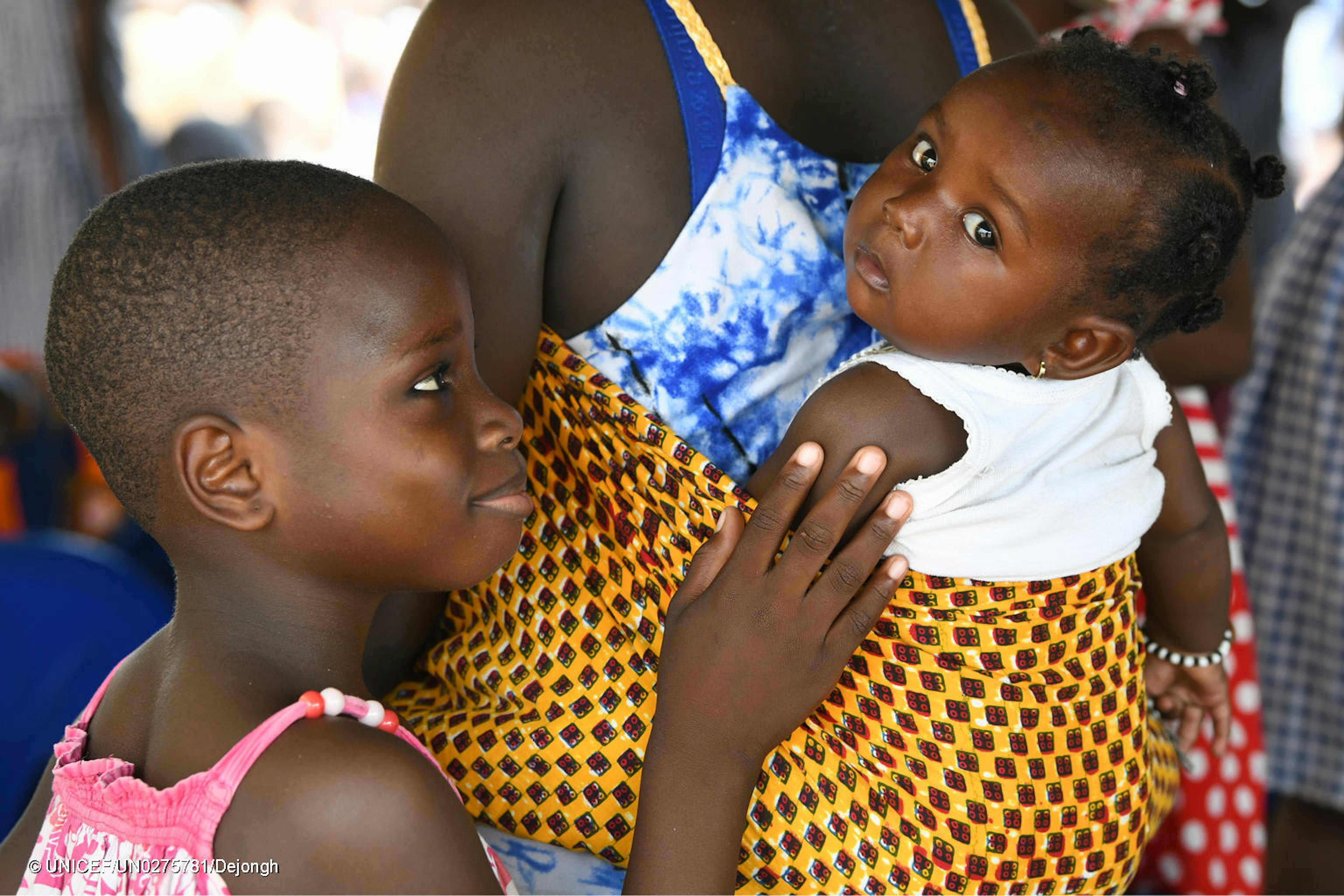 Una bambina accarezza la sorellina mentre si trova in braccio alla madre, a Gonzagueville, in the South of Abidjan.