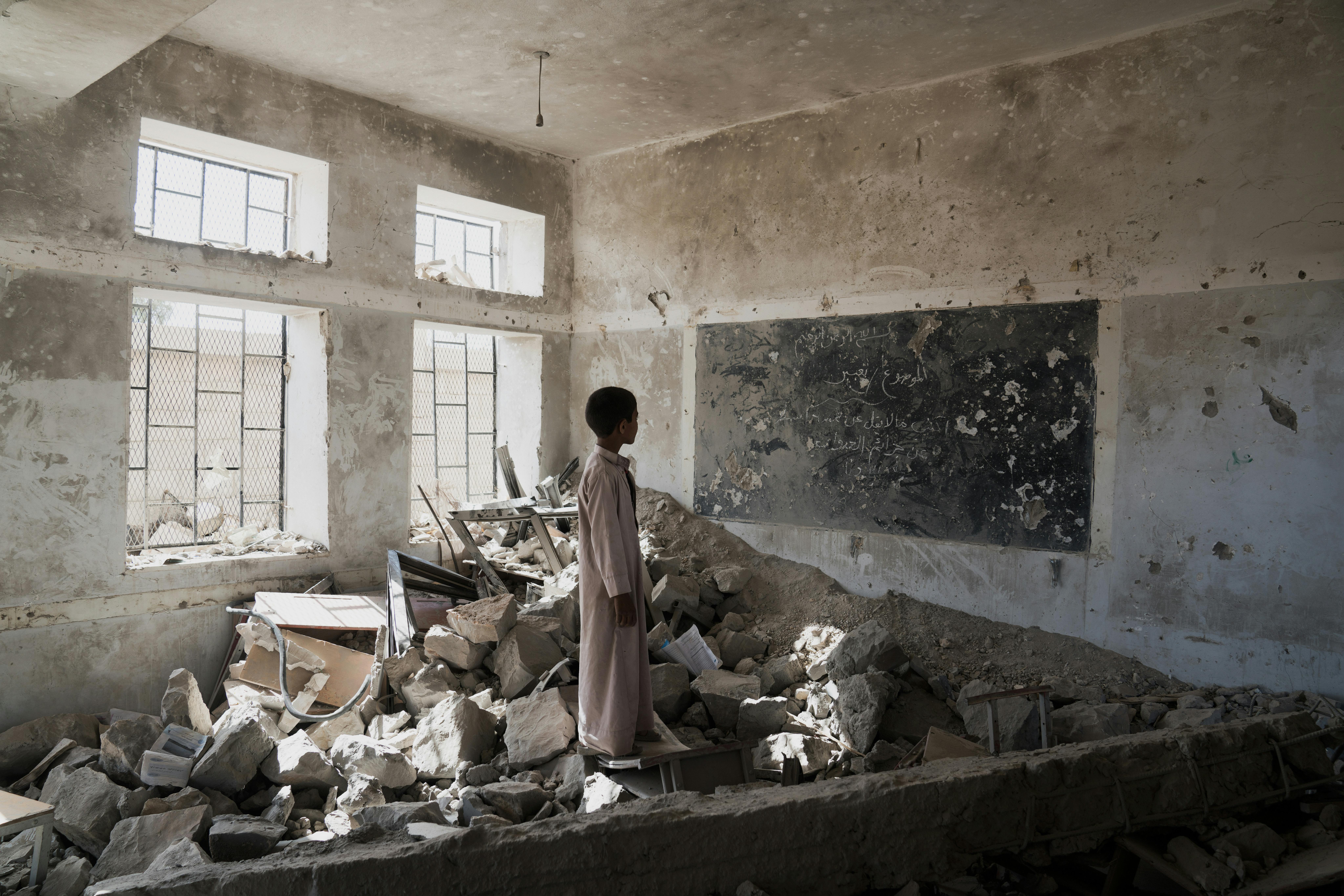 Yemen, uno studente tra le rovine della sua ex aula, distrutta nel giugno 2015, nella scuola Aal Okab di Saada, nel governatorato di Saada