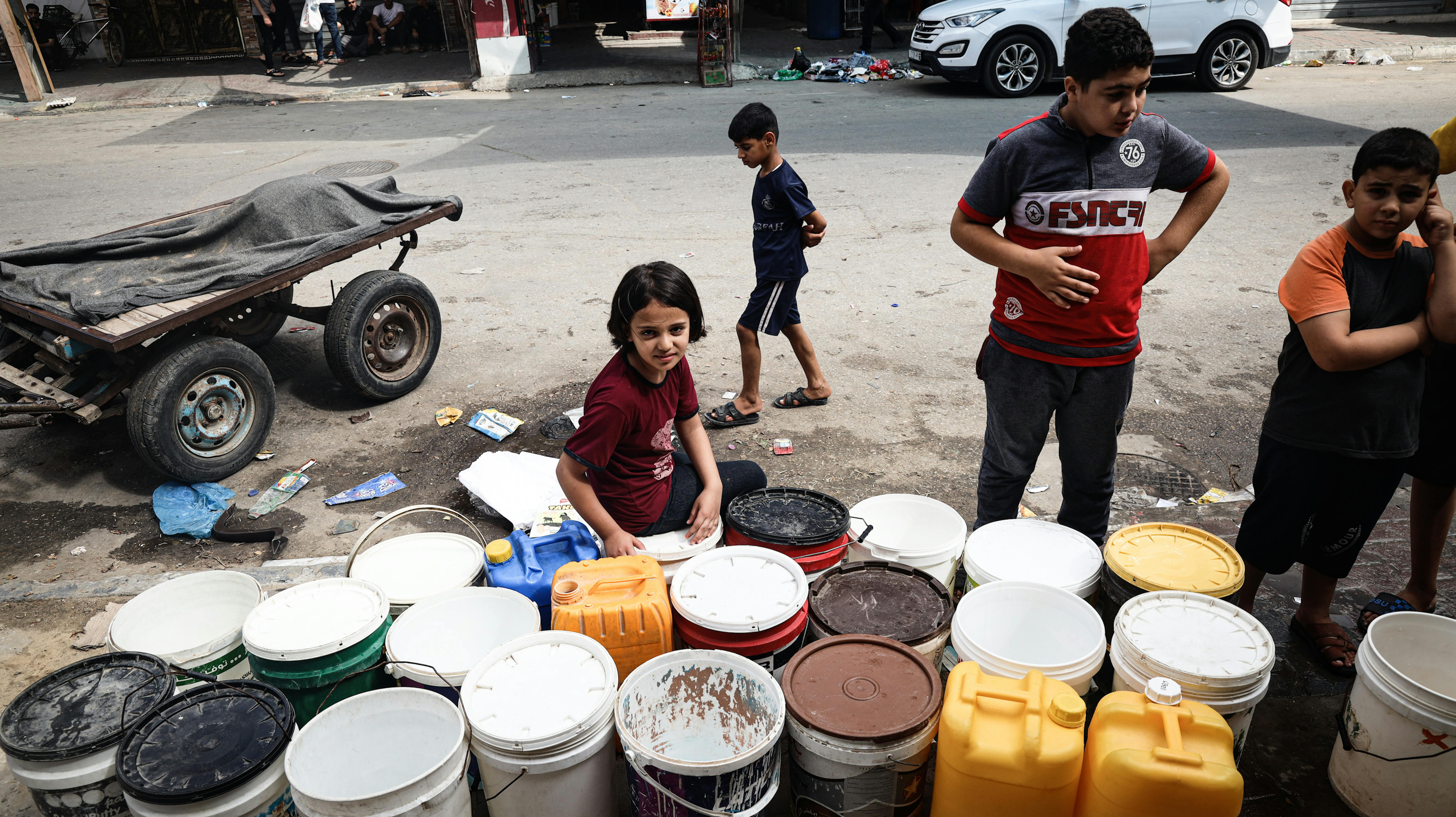 Bambini raccolgono acqua nella città di Rafah, nel sud della Striscia di Gaza, nel mezzo dell’escalation delle ostilità