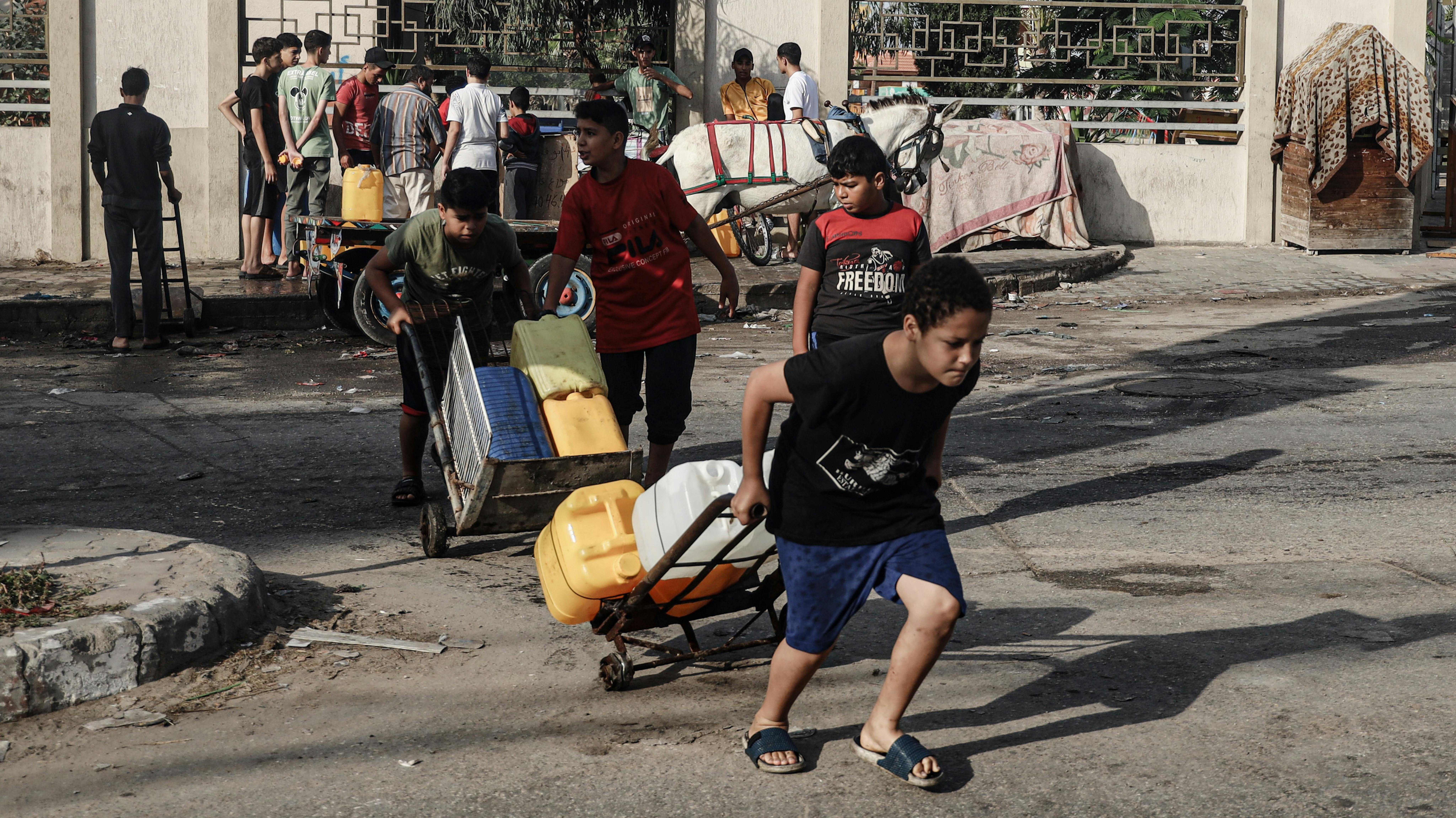Bambini raccolgono acqua nella città di Rafah, nel sud della Striscia di Gaza, nel mezzo dell’escalation delle ostilità