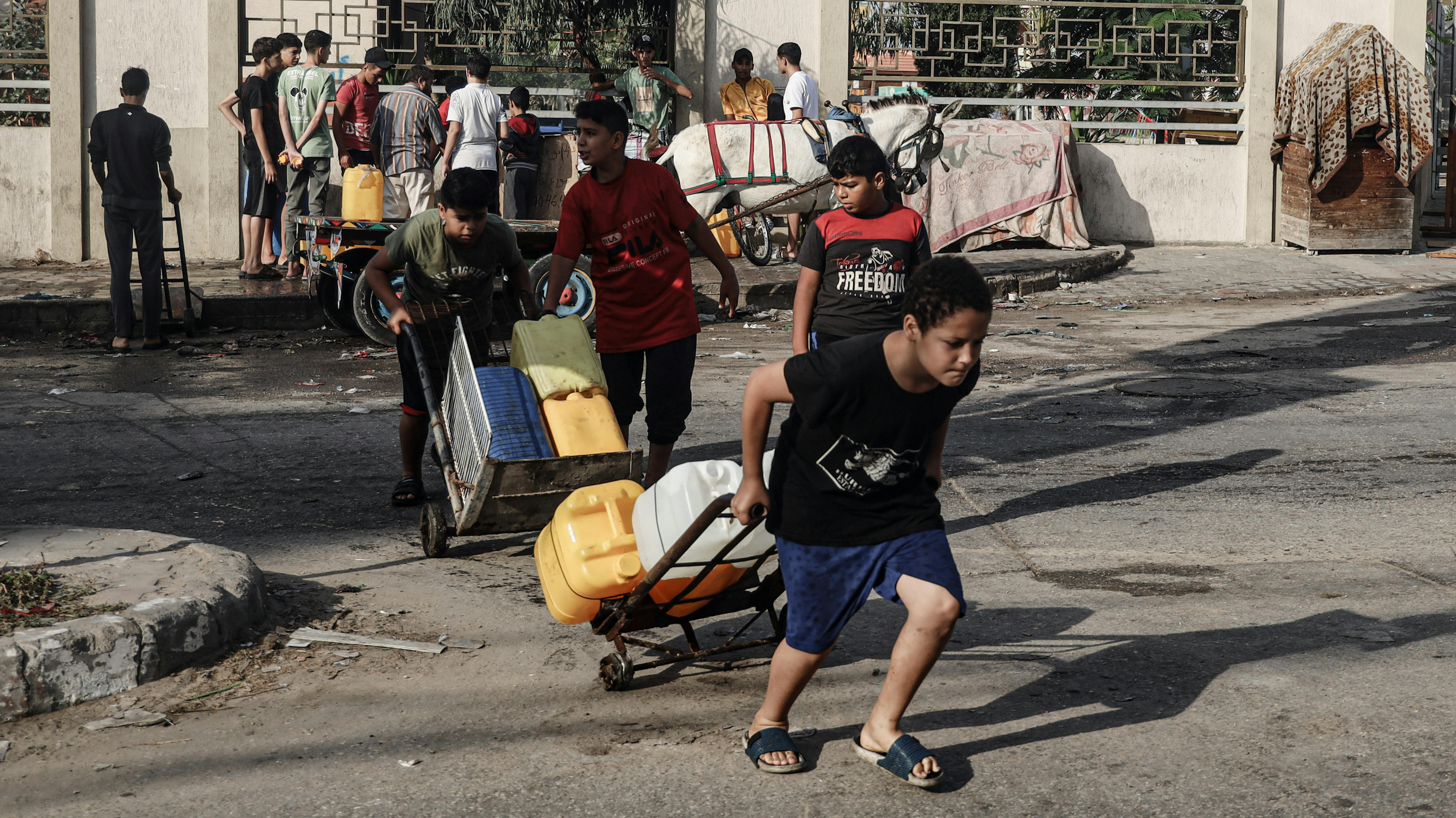 Bambini raccolgono acqua nella città di Rafah, nel sud della Striscia di Gaza, nel mezzo dell’escalation delle ostilità