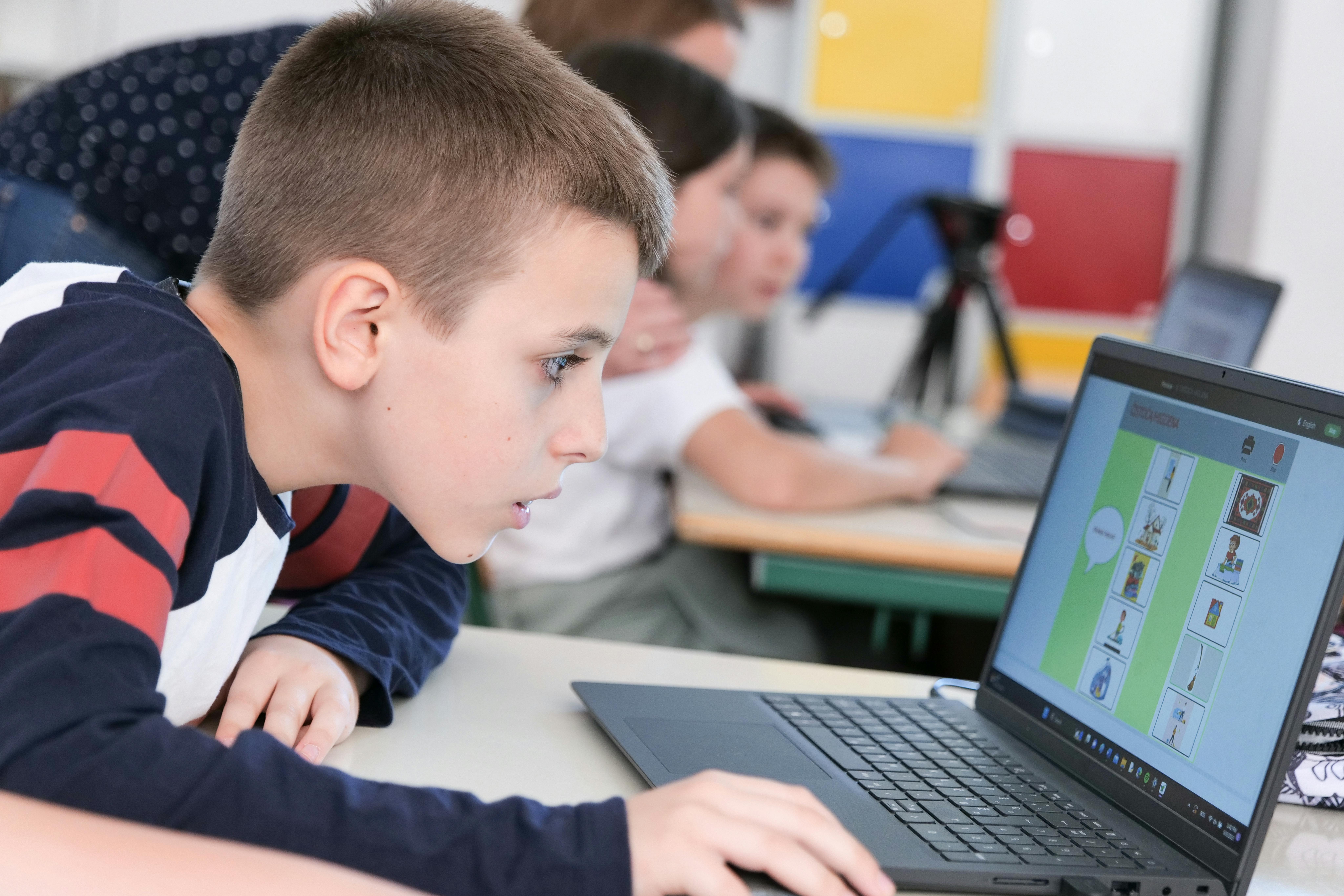 Questo bambino è molto concentrato, mentre naviga sul computer in un'aula scolastica