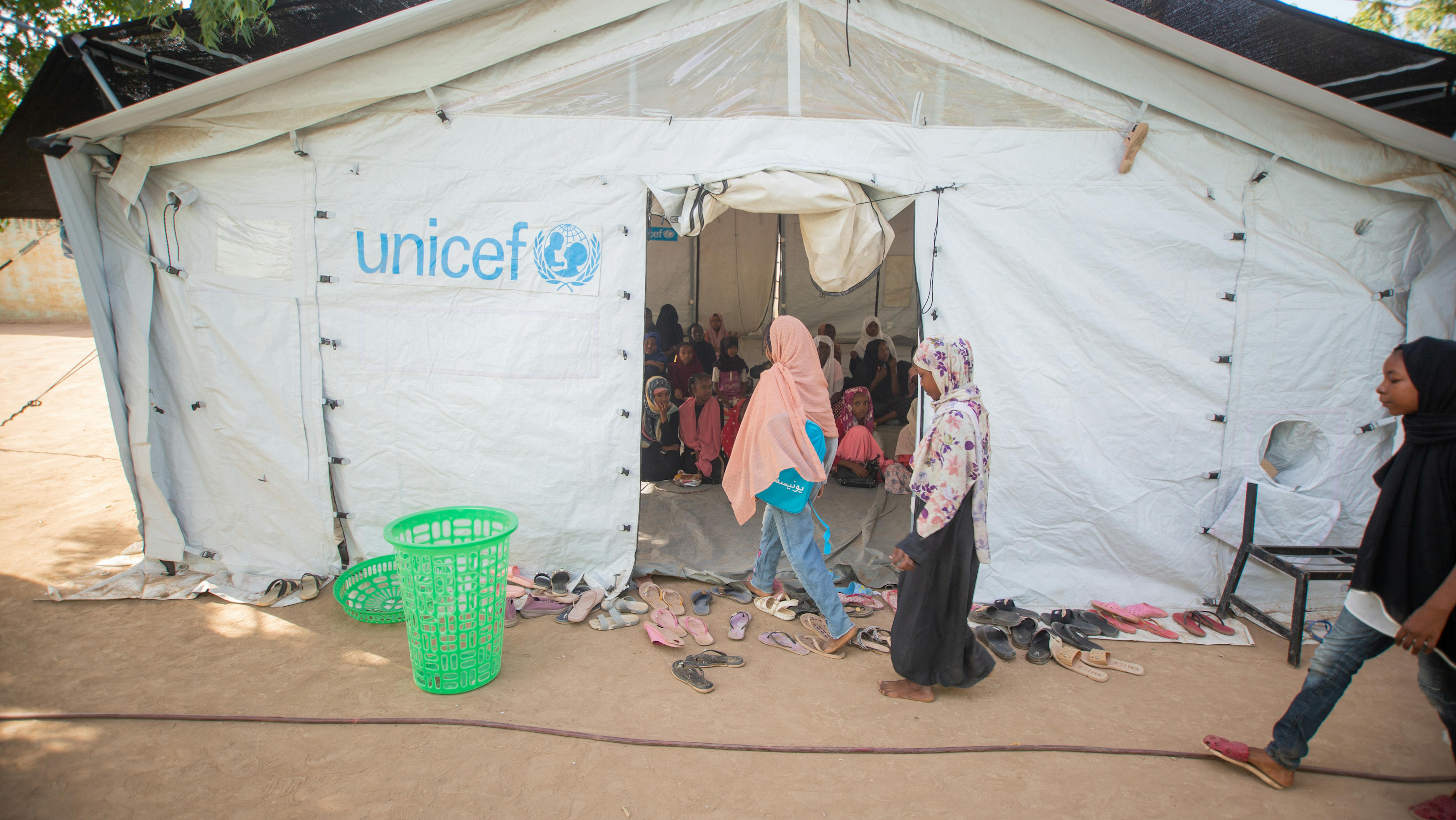 I bambini entrano in un'aula temporanea per svolgere attività in uno spazio di apprendimento sicuro (SLS) allestito dall'UNICEF