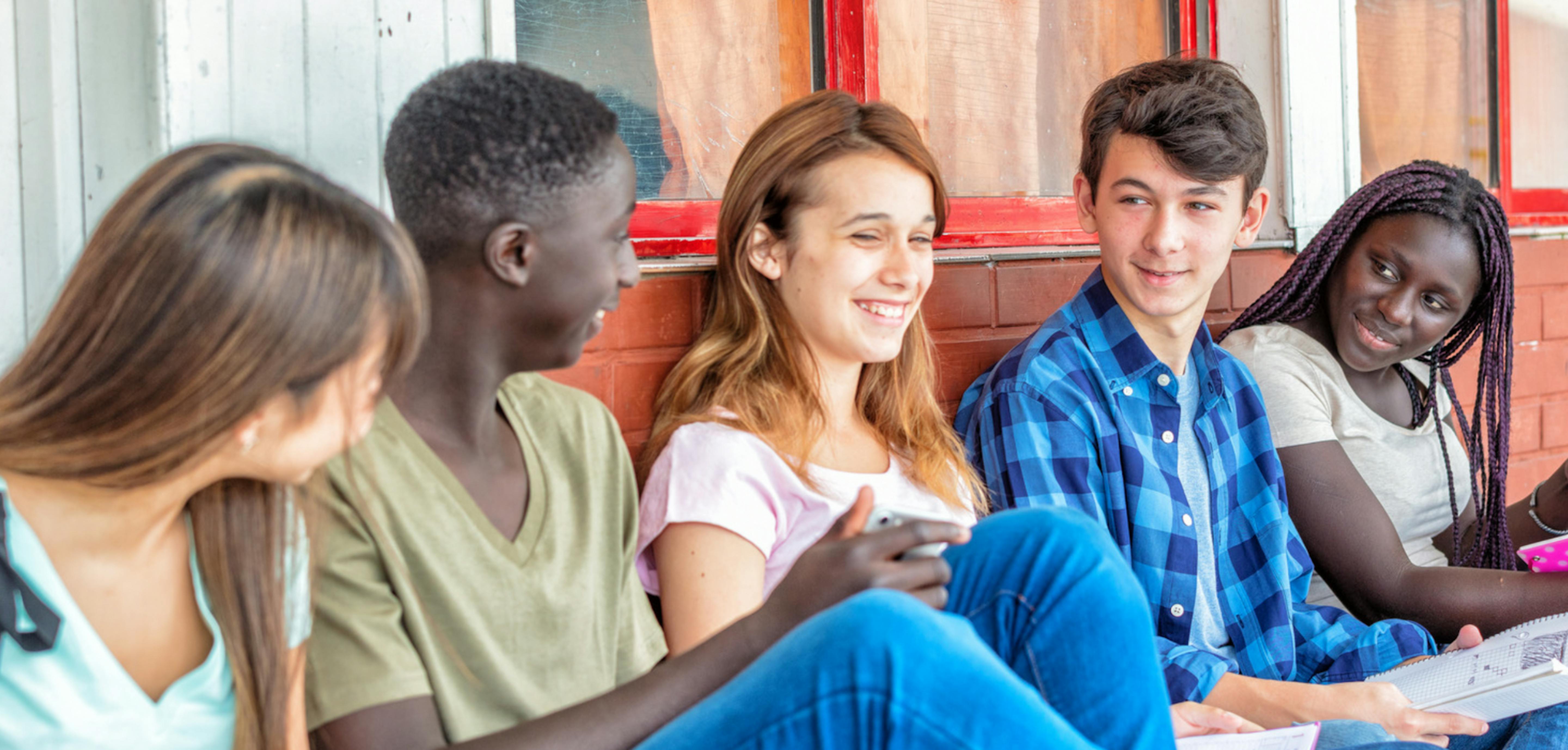 Adolescenti che chiacchierano appoggiati a un muro