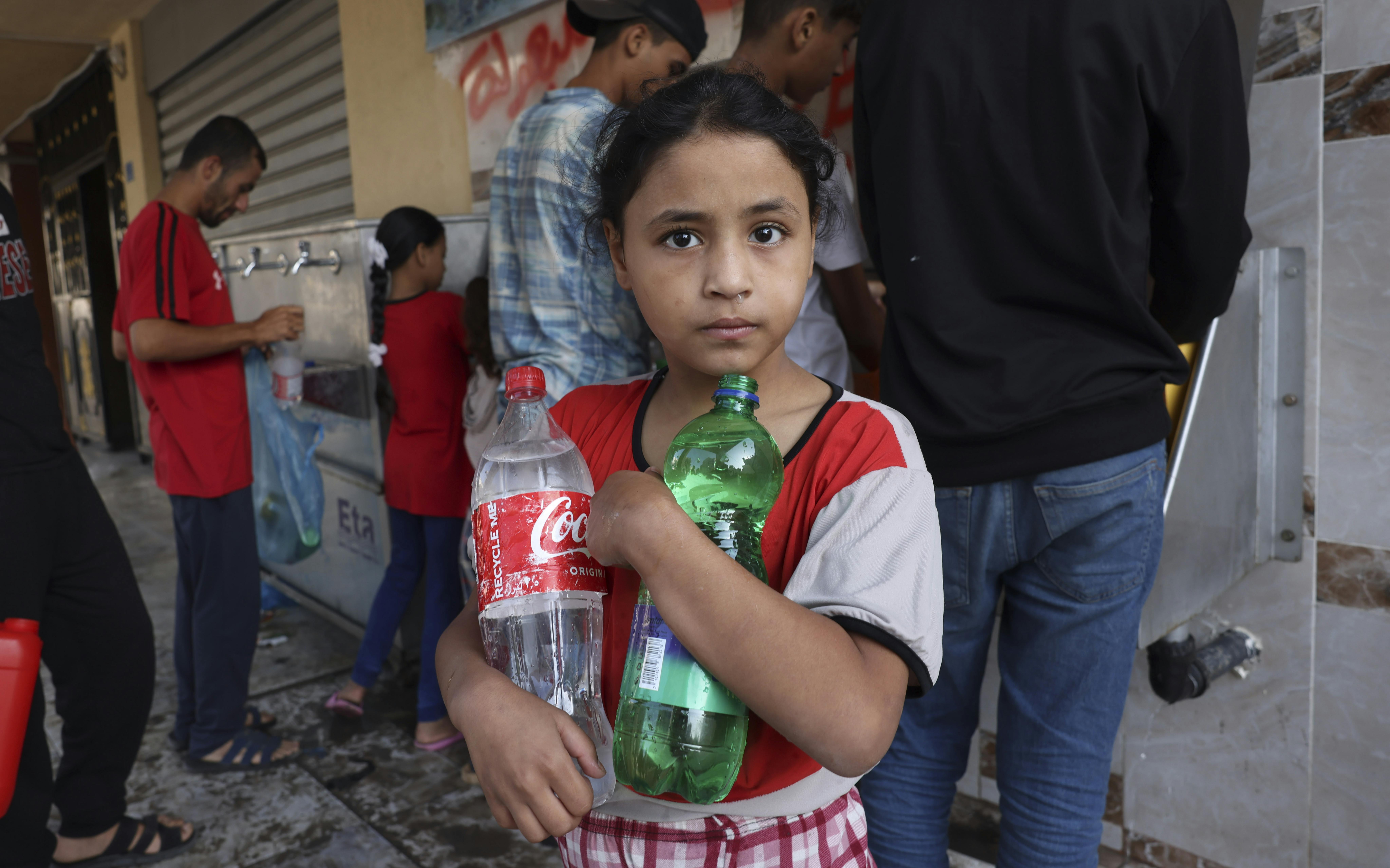 Rahaf, 7 anni, riempie bottiglie di acqua potabile nella città di Rafah, nel mezzo delle continue ostilità nella Striscia di Gaza