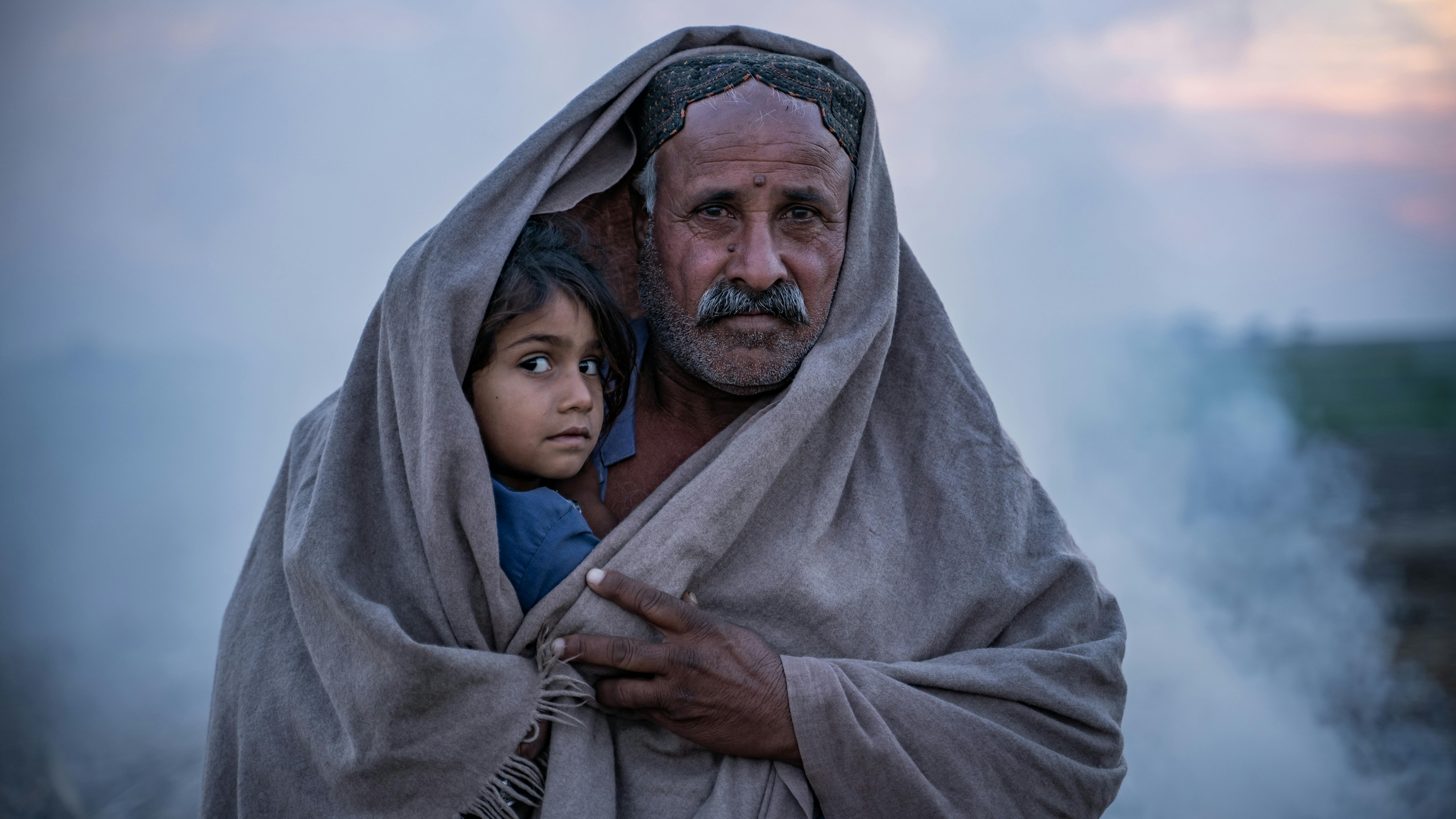 Pakistan -  Khan copre se stesso e sua figlia Nargis di 4 anni con uno scialle fuori dalla sua tenda nel villaggio di Zangi Brohi, distretto di Dadu, Sindh.