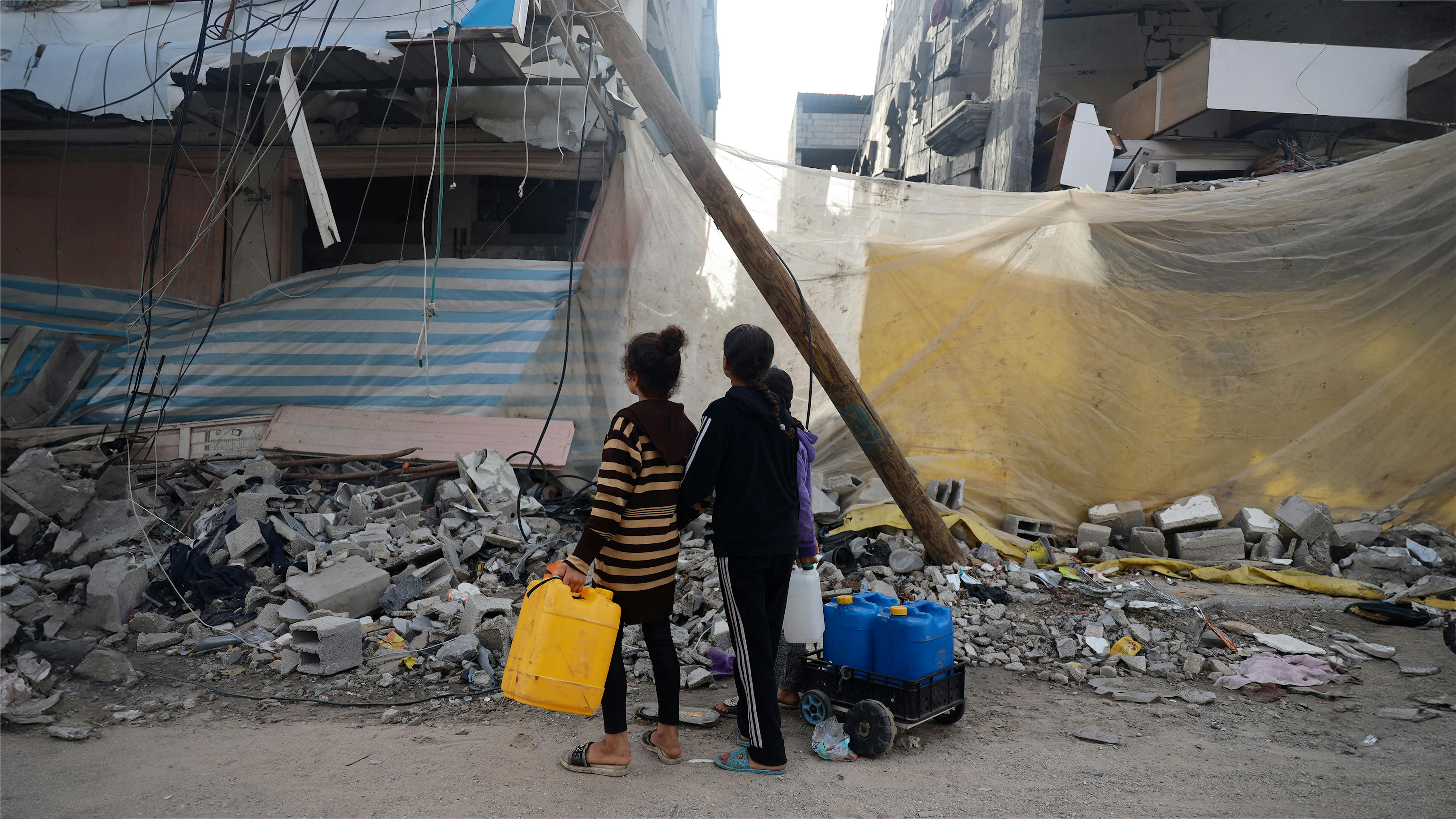 Bambini che raccolgono acqua nella città di Khan Younis, a sud della Striscia di Gaza, nel mezzo dell’escalation delle ostilità