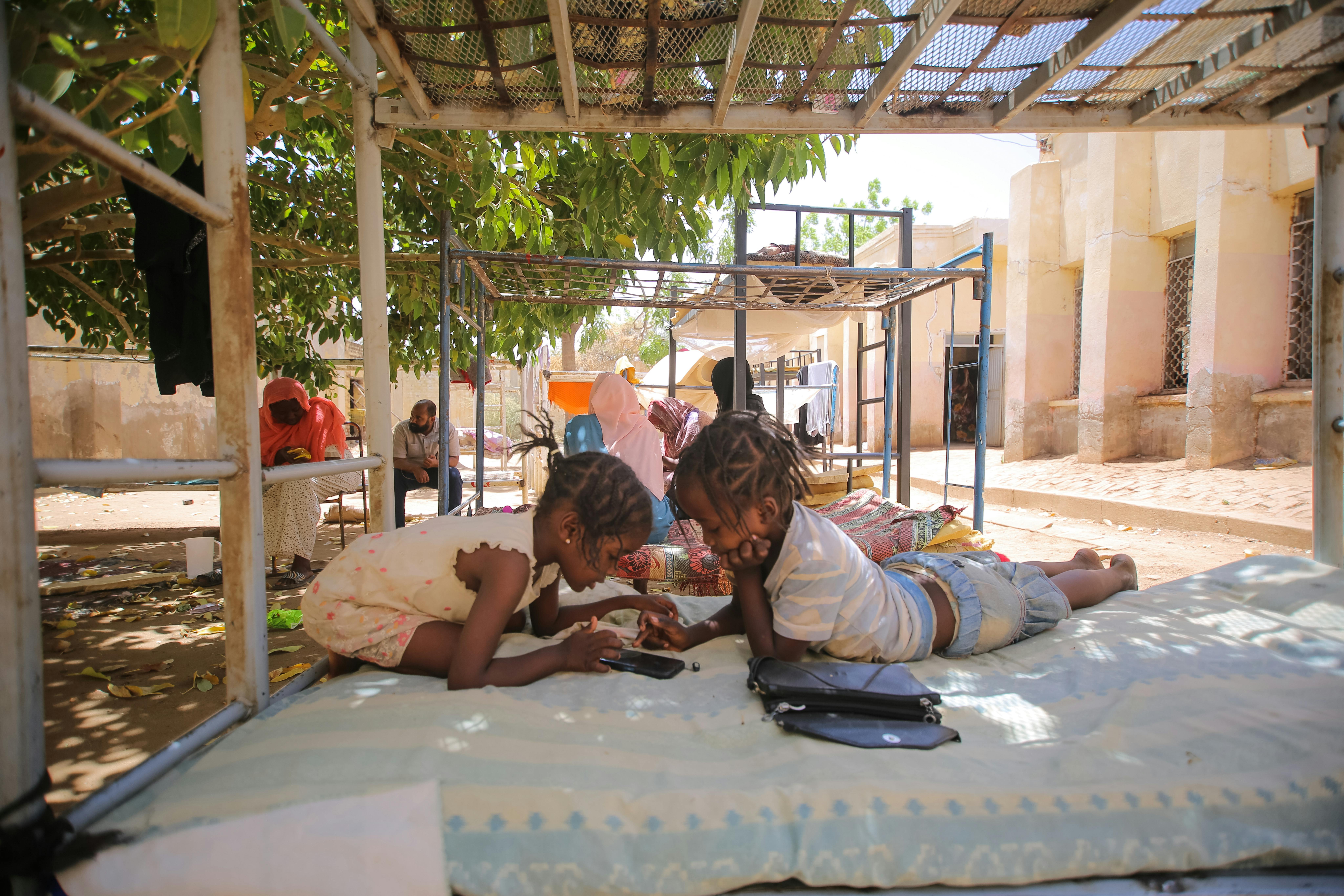 Sudan, bambini sfollati giocano con il cellulare in un rifugio temporaneo. ©UNICEF/UN0844224/Mohamdeen