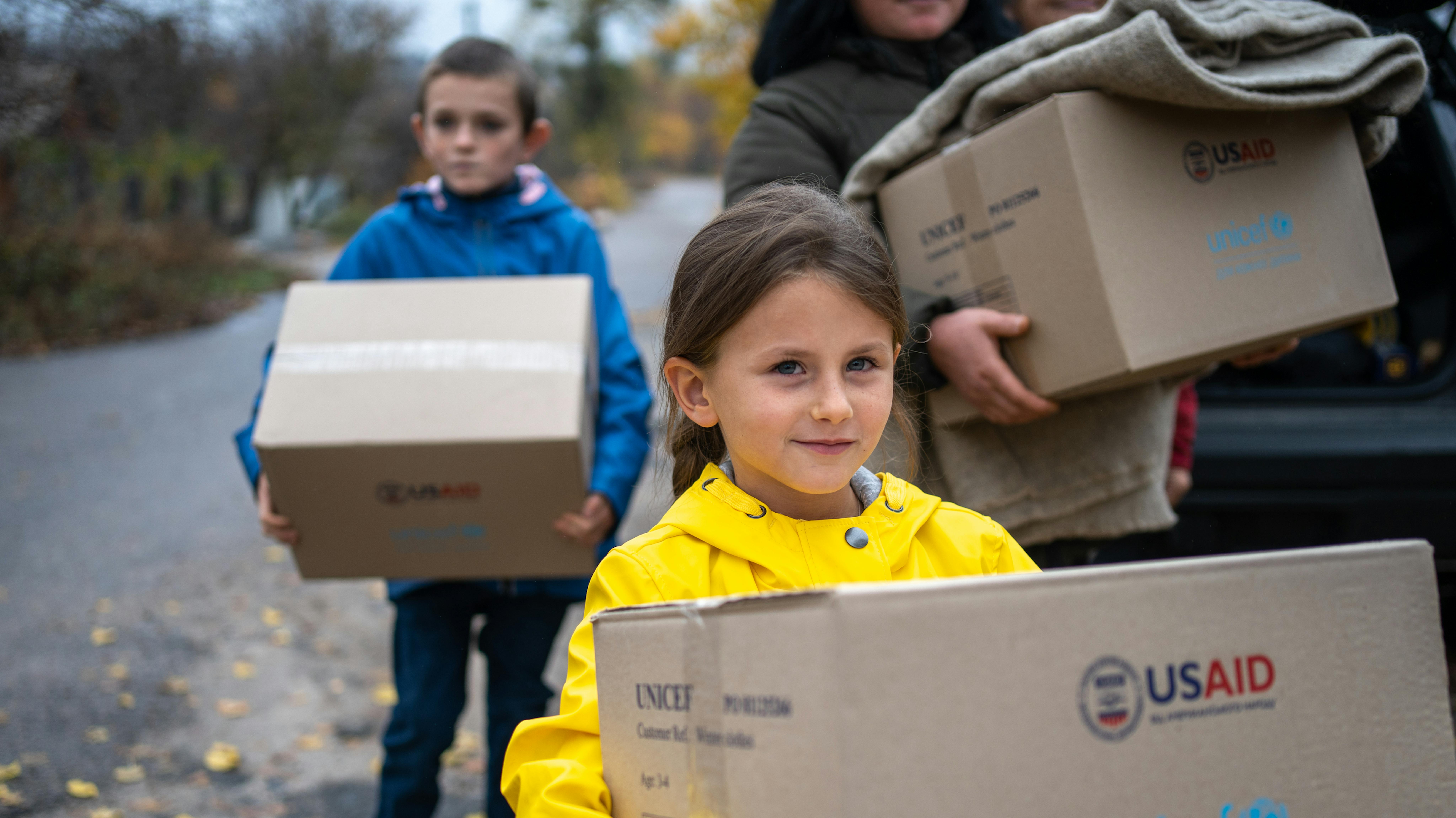 . Ucraina Vika (8) porta con sé una scatola di vestiti invernali, ricevuti dall'UNICEF. Suo fratello Sasha è dietro di lei.