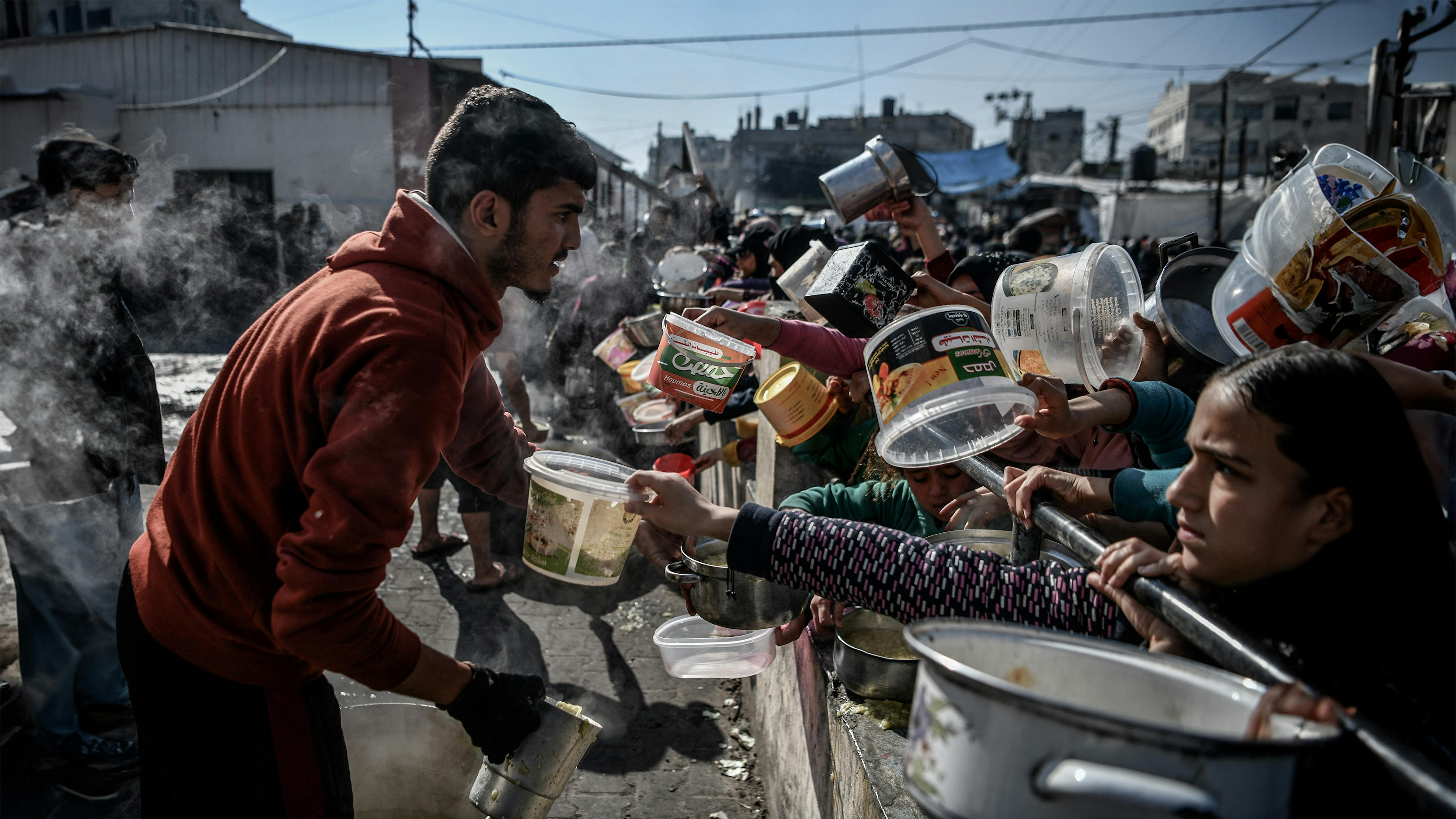 Stato di Palestina - Bambini aspettano in fila per ricevere una piccola quantità di cibo nella città di Rafah, nel sud della Striscia di Gaza.