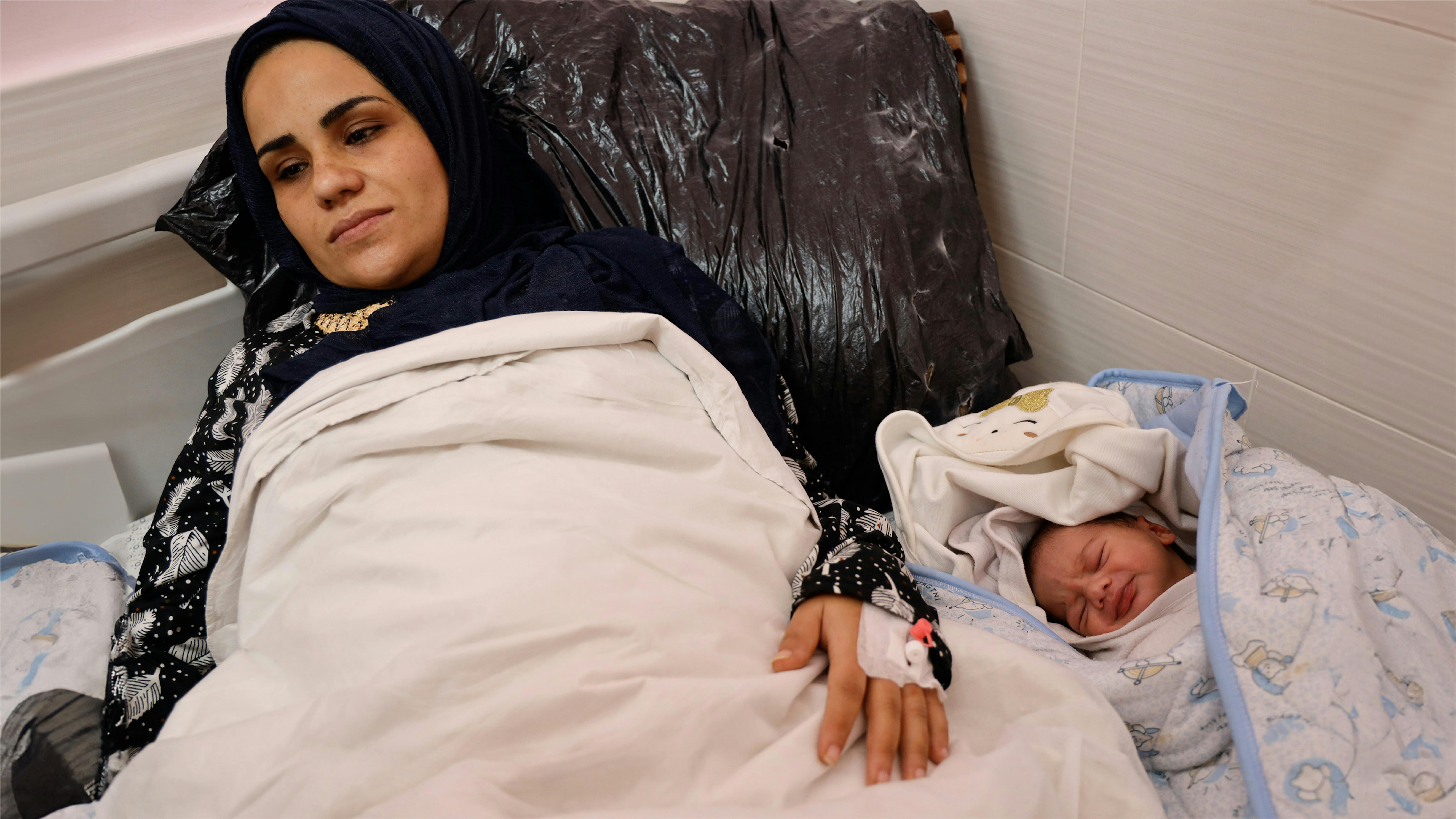 Stato di Palestina, una donna ricoverata accanto al suo neonato nell'Stato di Palestina, Iman (a destra) e Mashael siedono insieme su un letto nell'Emirati Maternity Hospital, a Rafah.