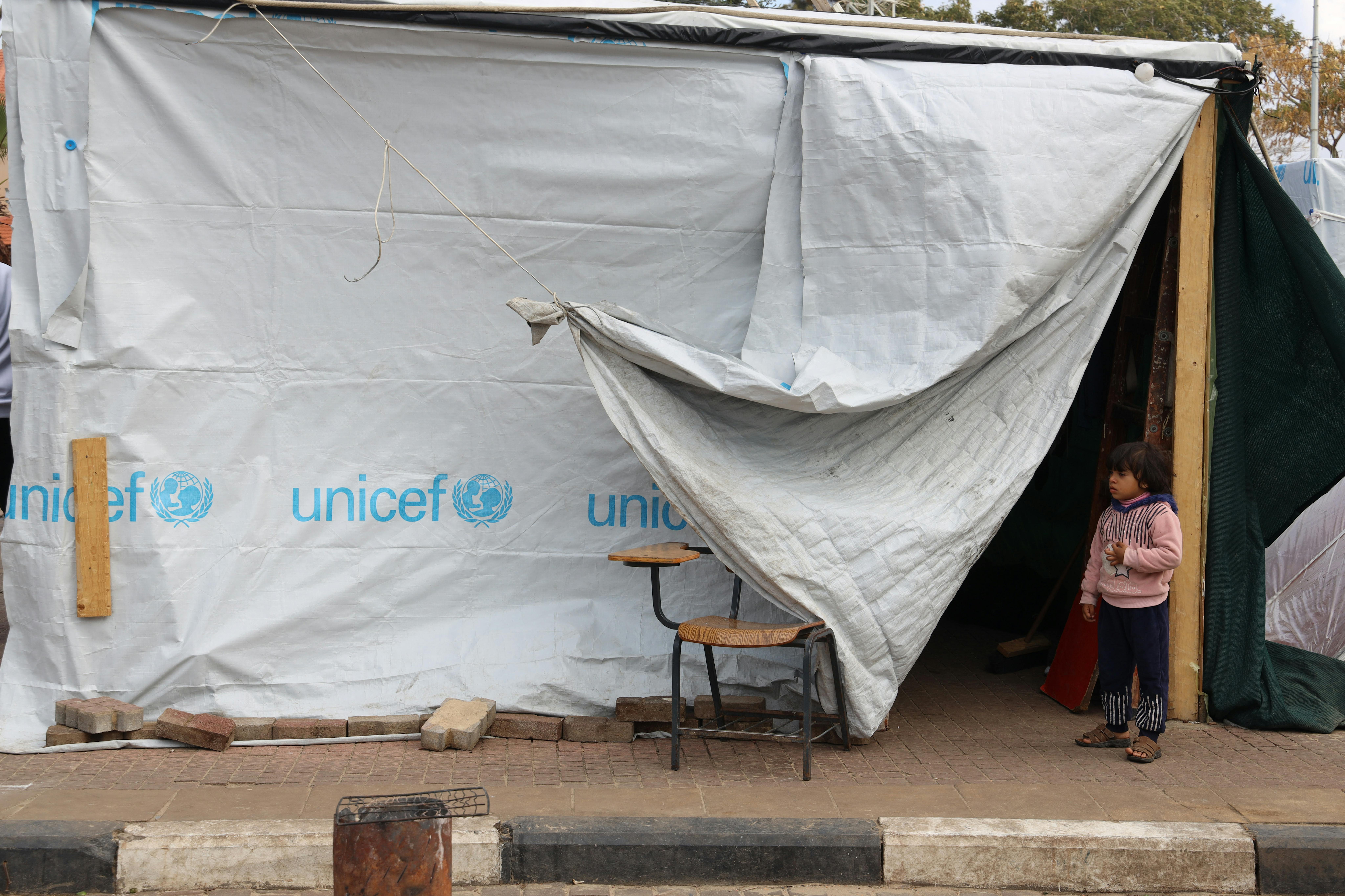 L’11 gennaio 2024, un bambino si trova accanto a una tenda dell’UNICEF in un centro di accoglienza nella Striscia di Gaza.