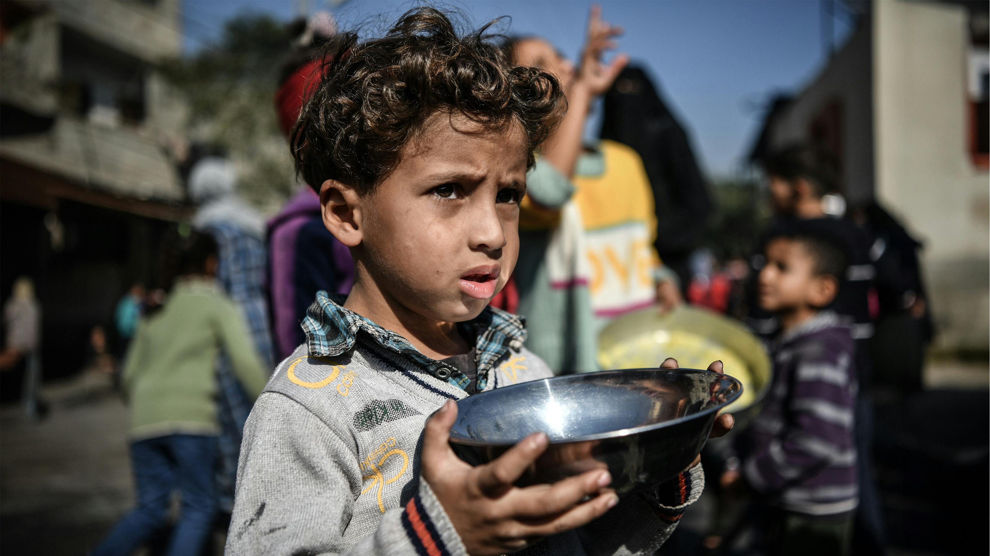 Ahmad, 5 anni, aspetta il suo turno tra la folla per ricevere un pasto da un ospizio di beneficenza che distribuisce cibo gratuito nella città di Rafah, nel sud della Striscia di Gaza.