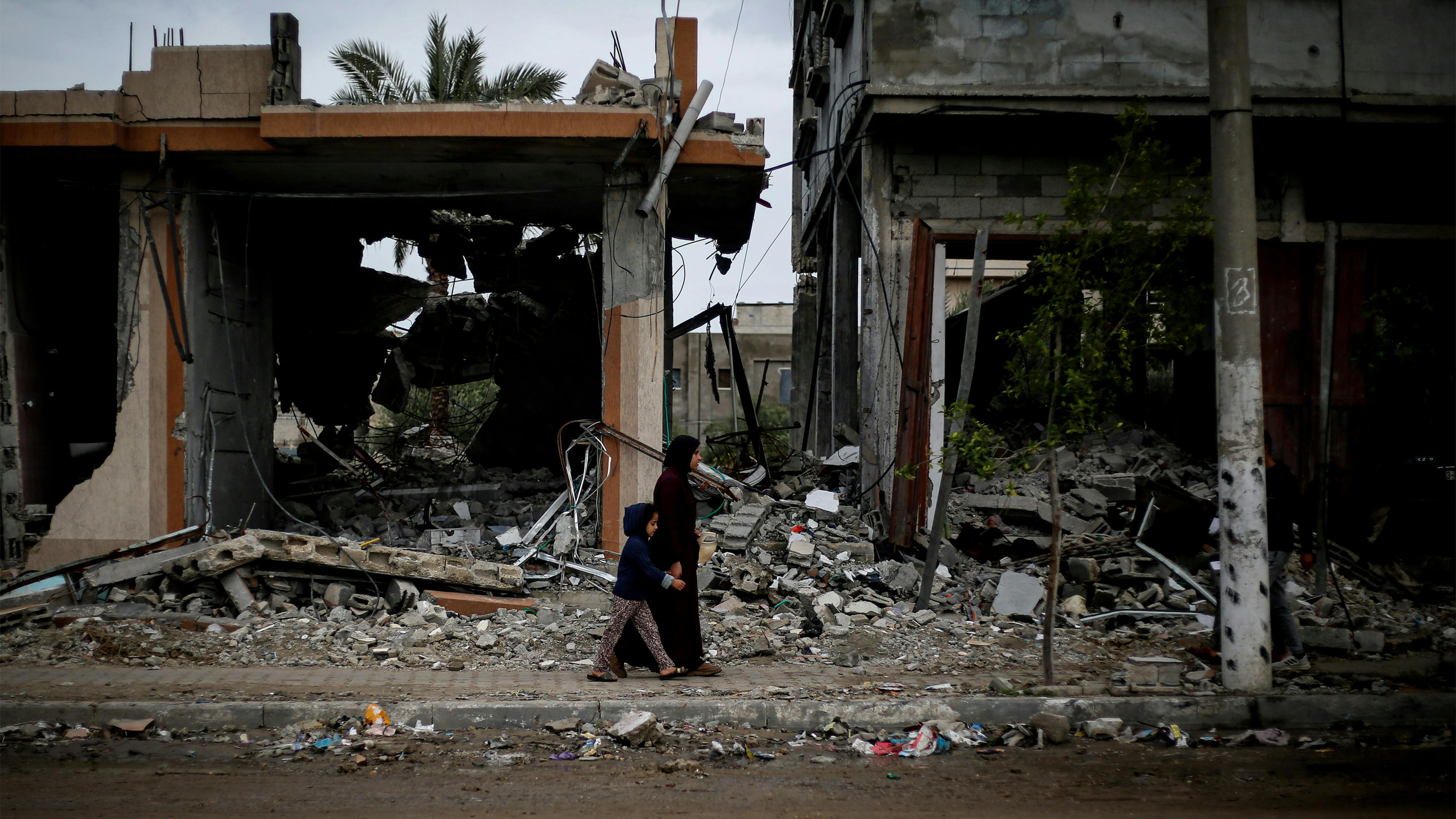 Una donna e suo figlio camminano tra le macerie delle case distrutte nella città di Rafah, a sud della Striscia di Gaza.