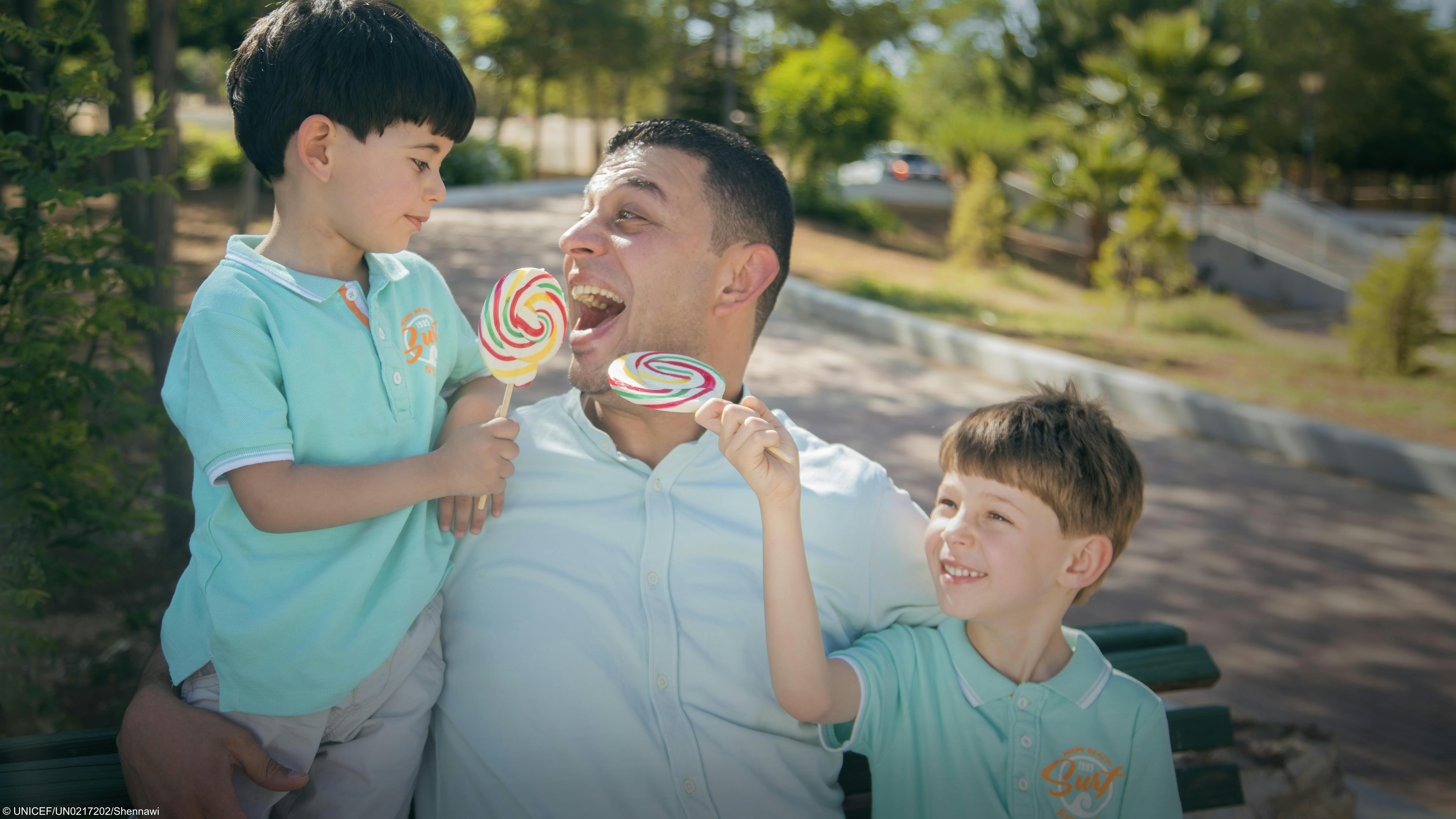 Papà e figli giocano al parco, con enormi caramelle. La foto è scattata in Giordania