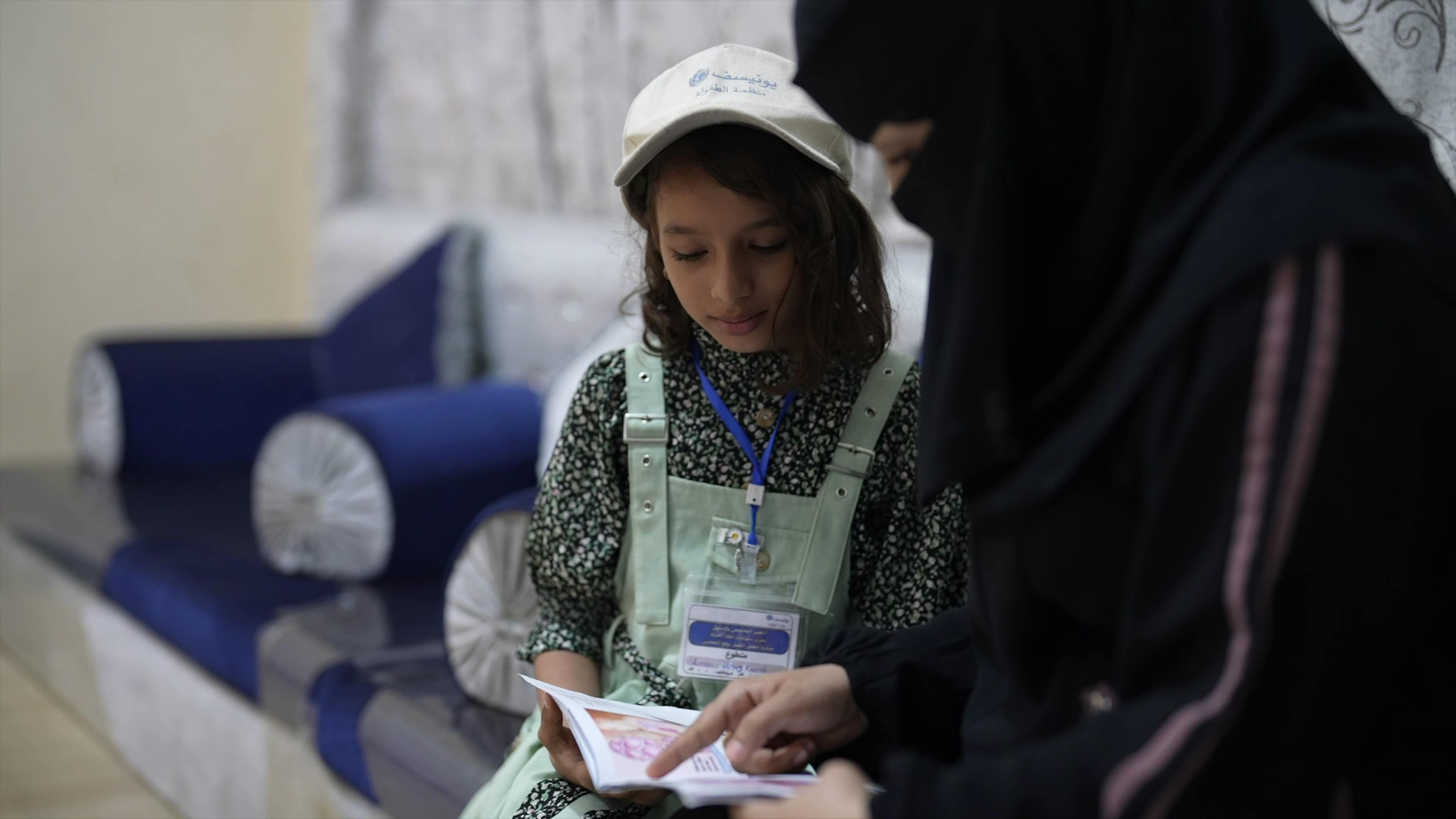 Leen Helmi e sua madre Samah Munir guardano il libretto delle vaccinazioni nella loro casa ad Aden, nello Yemen.