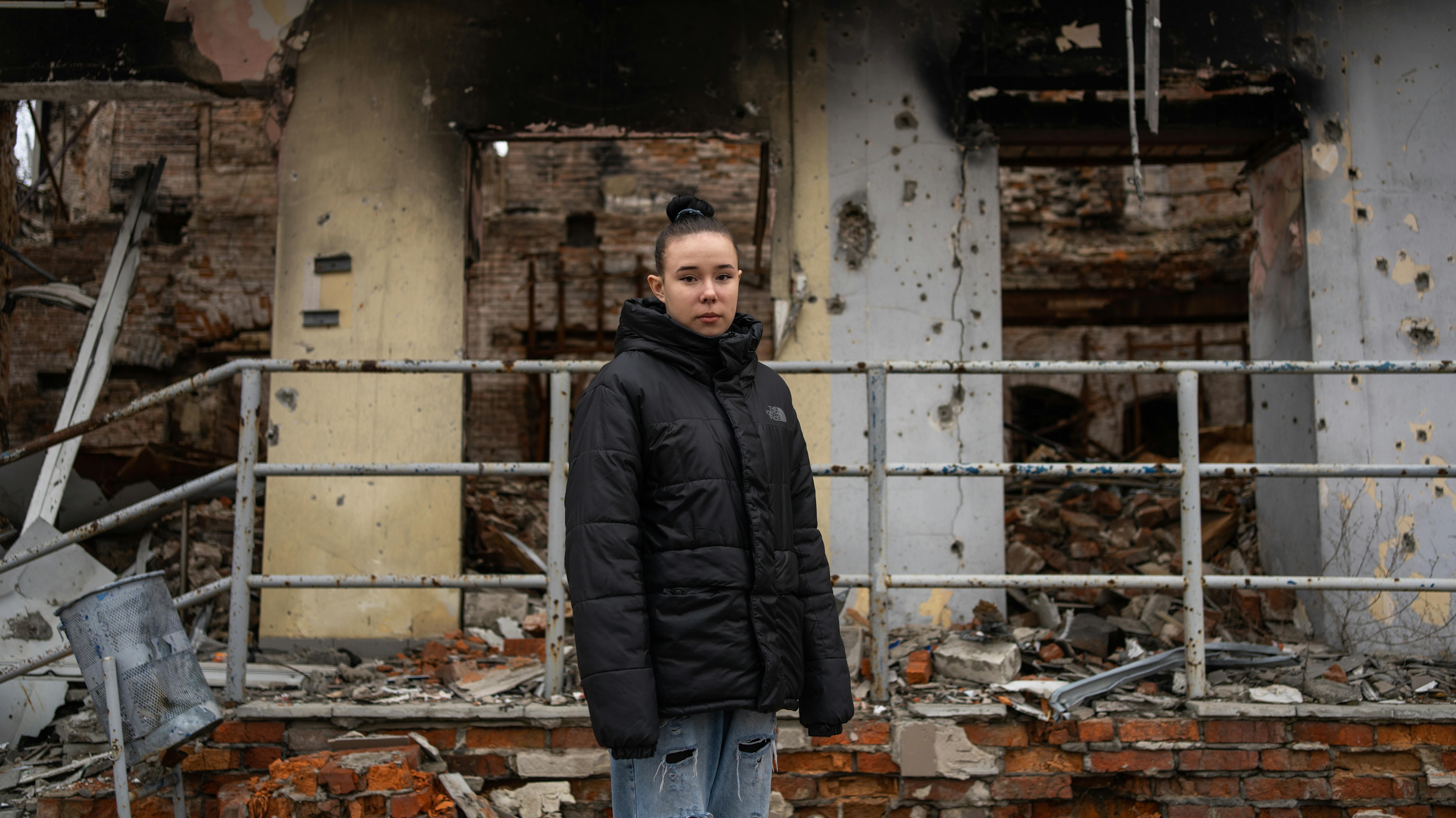 Zium, regione di Kharkivska, Ucraina. Nastia, 15 anni, sopravvissuta all'esplosione di una mina, si trova sullo sfondo di un edificio, trafitto da colpi di arma da fuoco e bombardamenti.