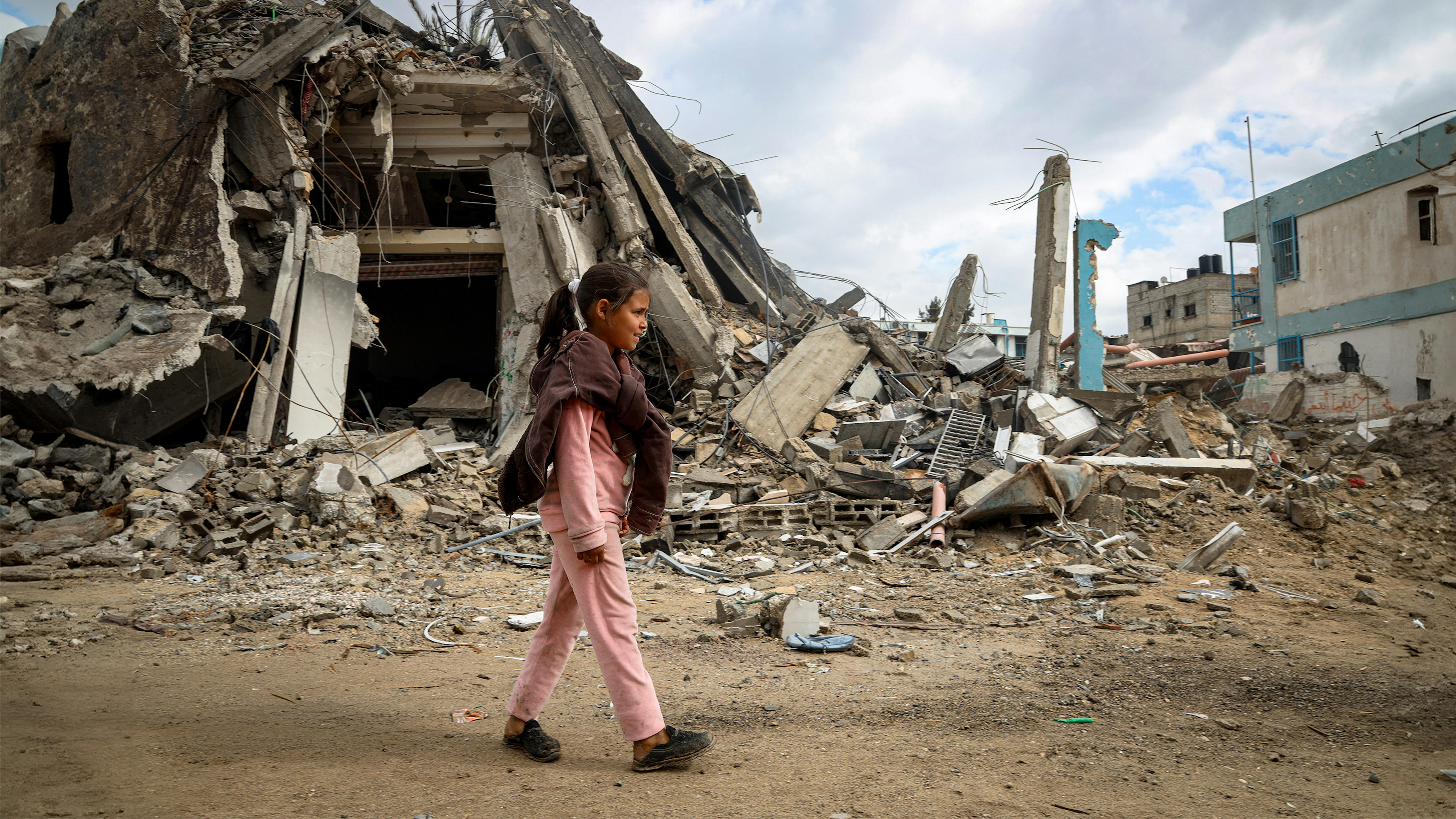 Sama, 10 anni, cammina tra le macerie del suo quartiere distrutto a Khan Younis, nel sud della Striscia di Gaza