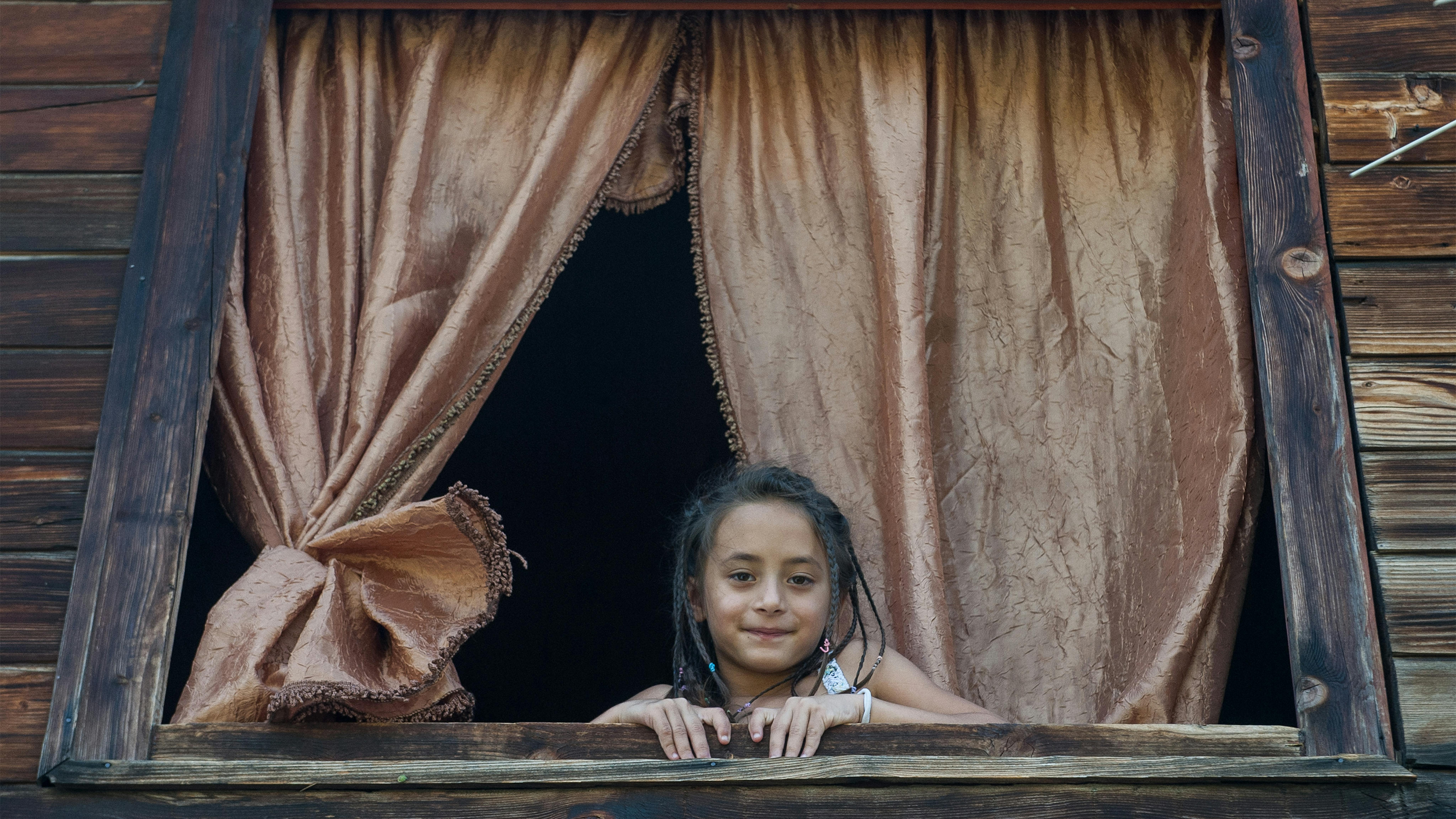 Serbia - Una bambina guarda fuori dalla finestra la sua casa