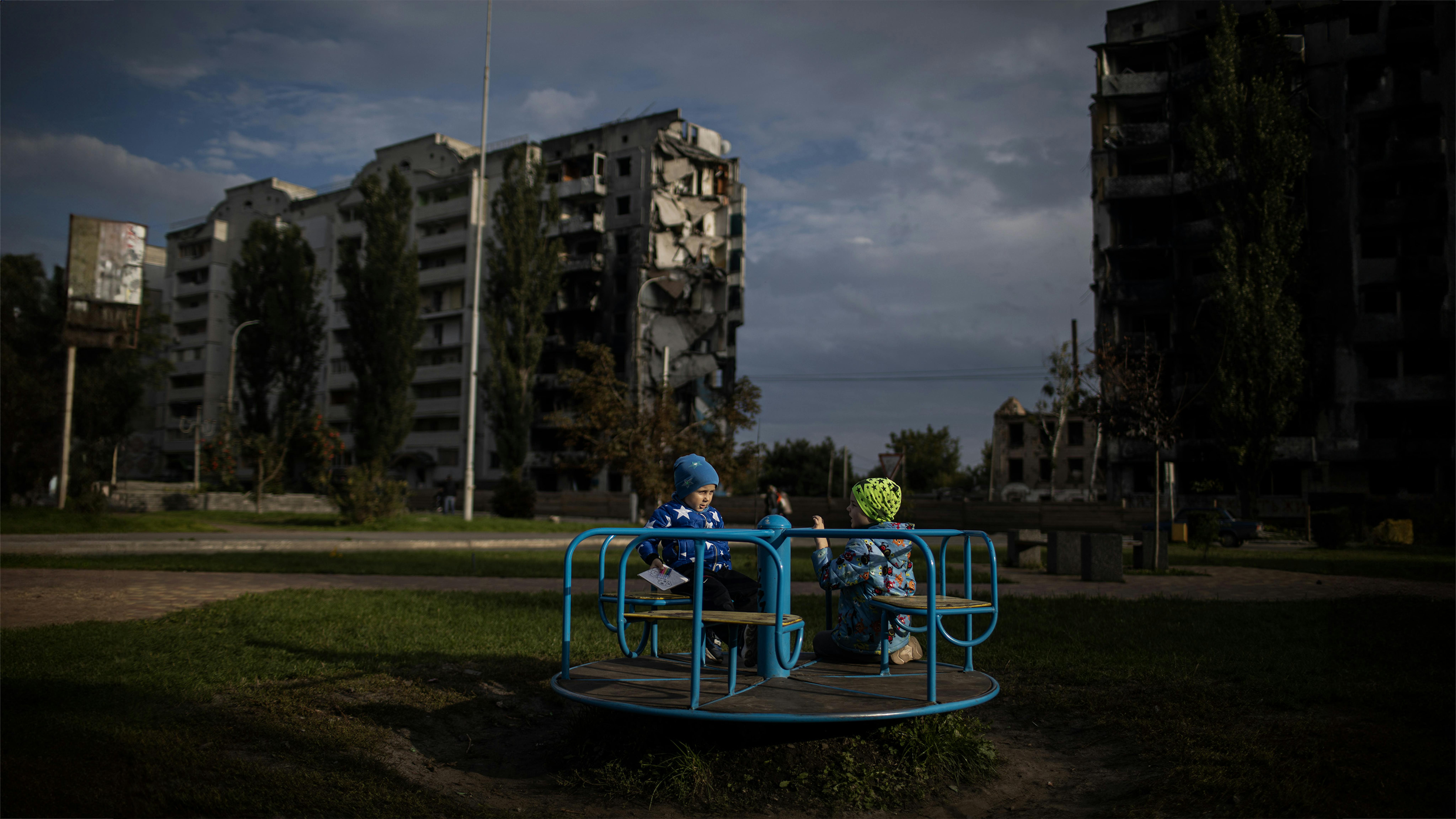Ucraina, i bambini giocano sullo sfondo degli edifici distrutti a Borodyanka.