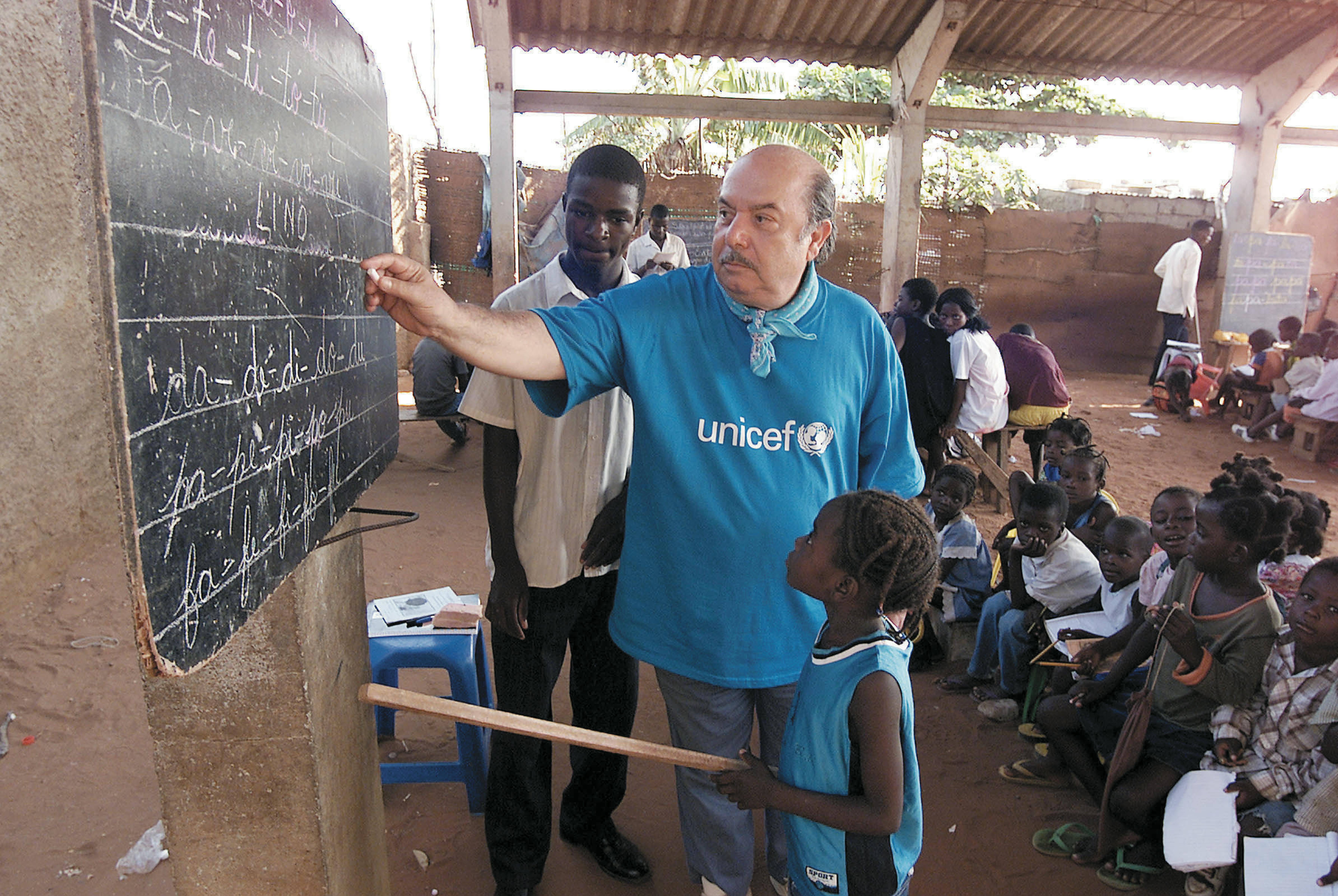 Lino Banfi con alcuni bambini di una classe allestita in una baraccopoli di Luanda, capitale dell’Angola, durante una missione con l’UNICEF nel marzo 2003.