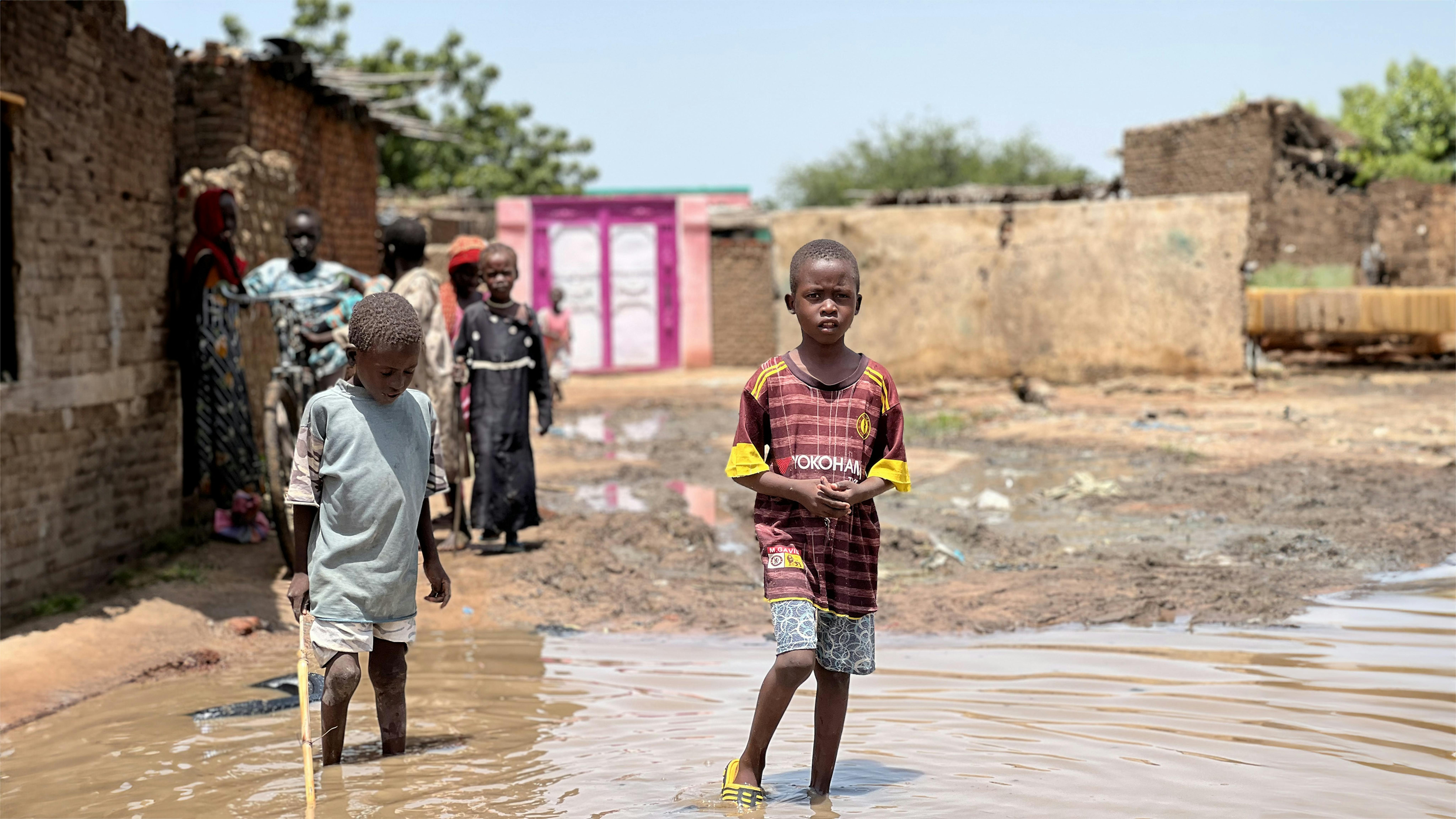 Un ragazzino cammina nell'acqua stagnante dopo forti piogge e inondazioni nel campo per sfollati interni di Kalma, nel Darfur meridionale.