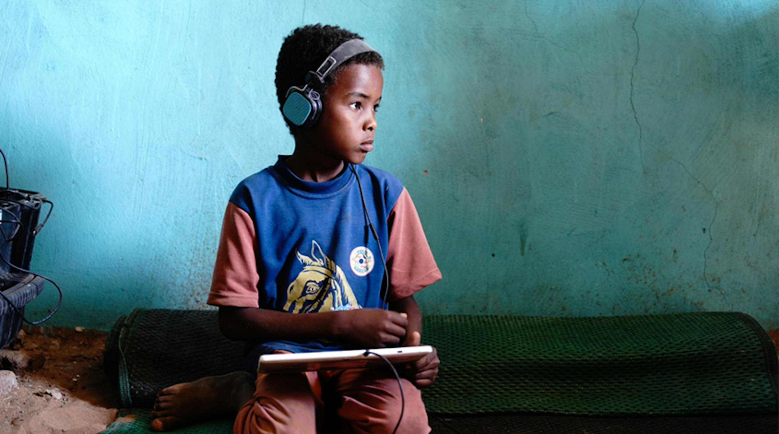 Mohammed (8 anni) sta giocando a un gioco di matematica sul suo tablet a energia solare nel centro di e-learning sostenuto dall'UNICEF a Jabalain, nello Stato del Nilo Bianco, in Sudan.