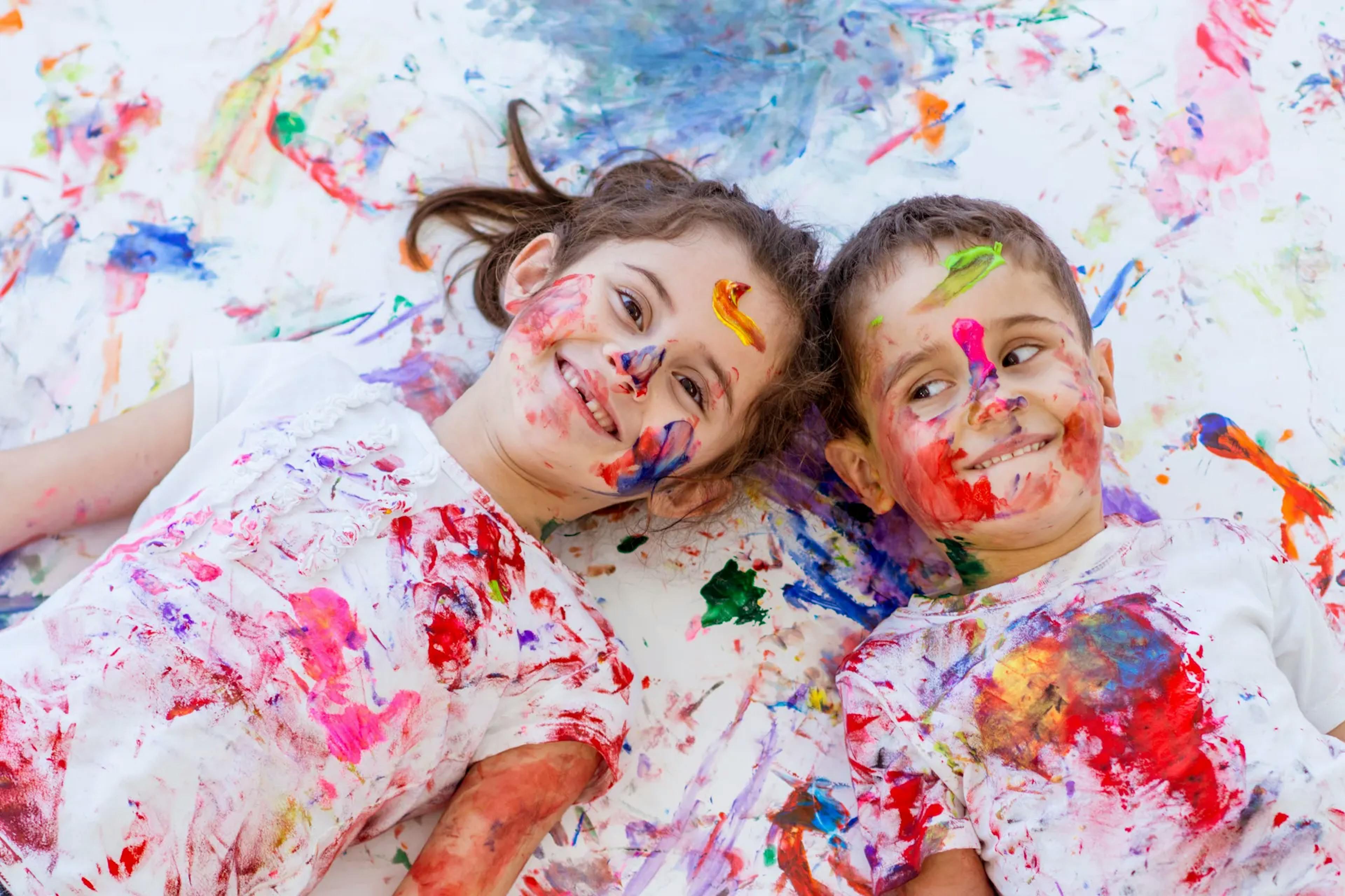 Bambina e bambino sporchi di colore, sdraiati a terra