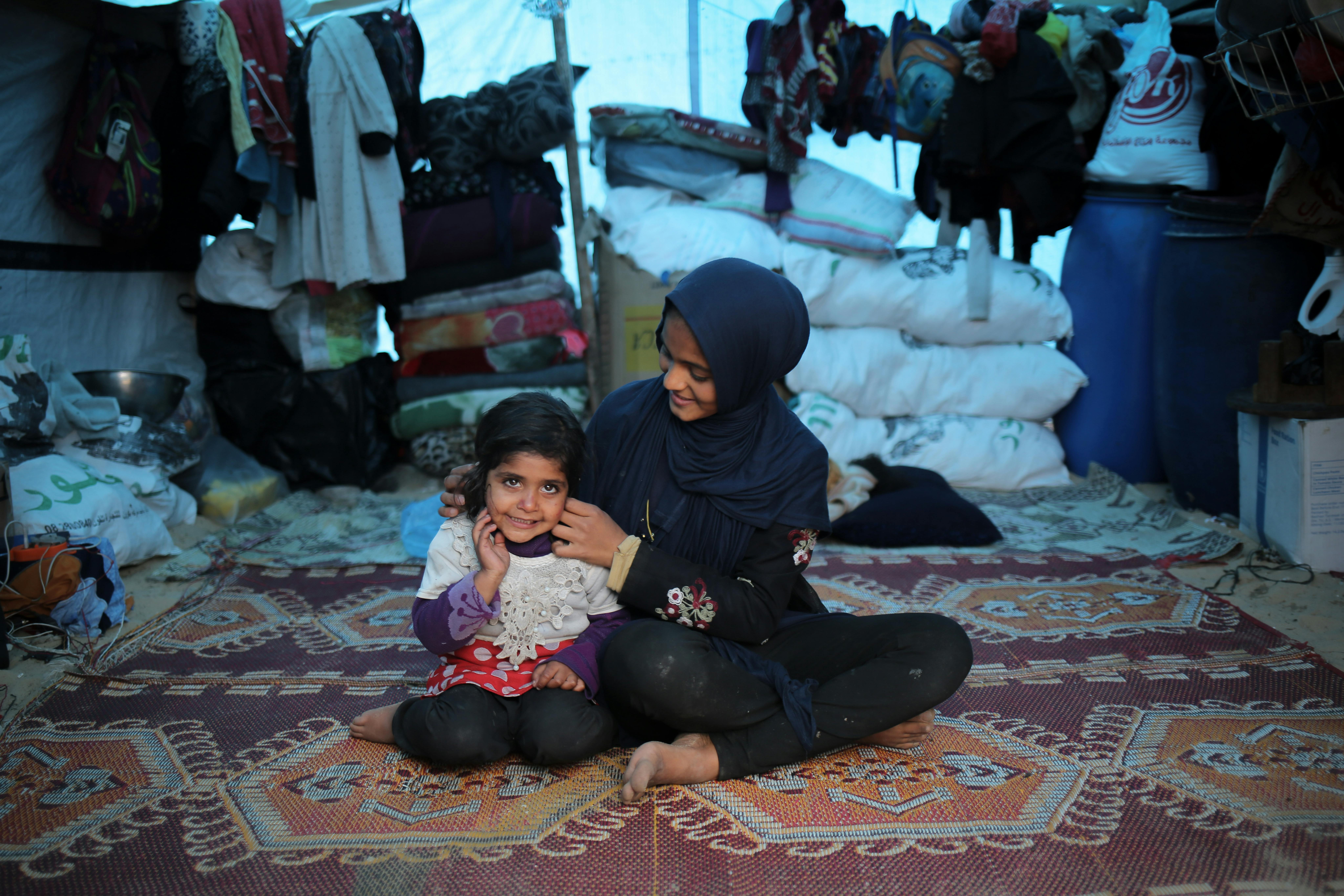 Duha, 14 anni, siede accanto a sua sorella Malak, 3 anni, nella loro tenda a Rafah, a sud della Striscia di Gaza. Duha è sorda, riceve il sostegno dell'UNICEF nello Stato di Palestina e usa il linguaggio dei segni per esprimersi e parlare della sua esperienza durante la guerra in corso.