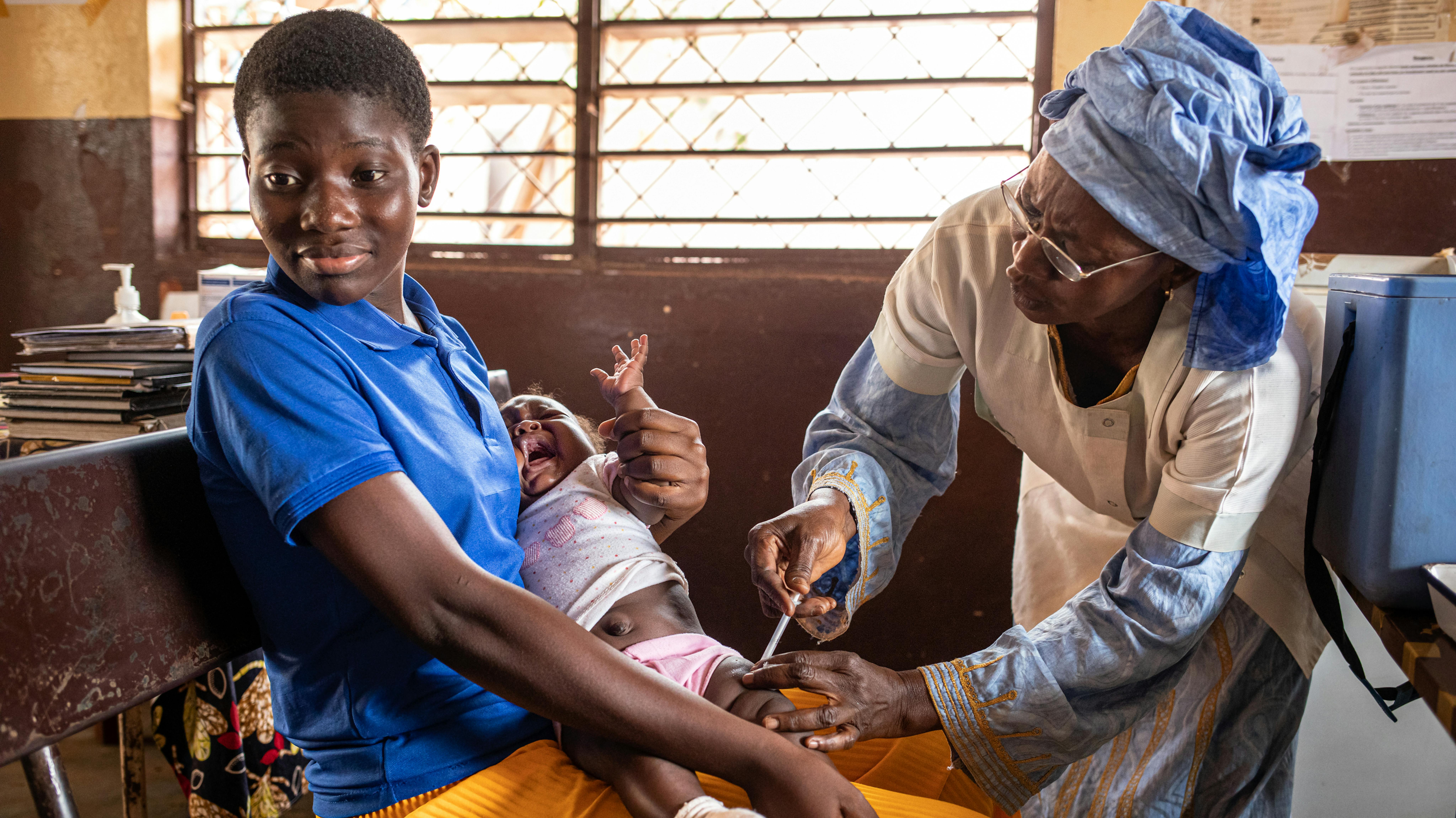 Repubblica Centrafricana, una bambina tenuta in braccio dalla madre mentre viene vaccinata dall'operatrice sanitaria Celestine Koursany al Centre de Santé Urbain