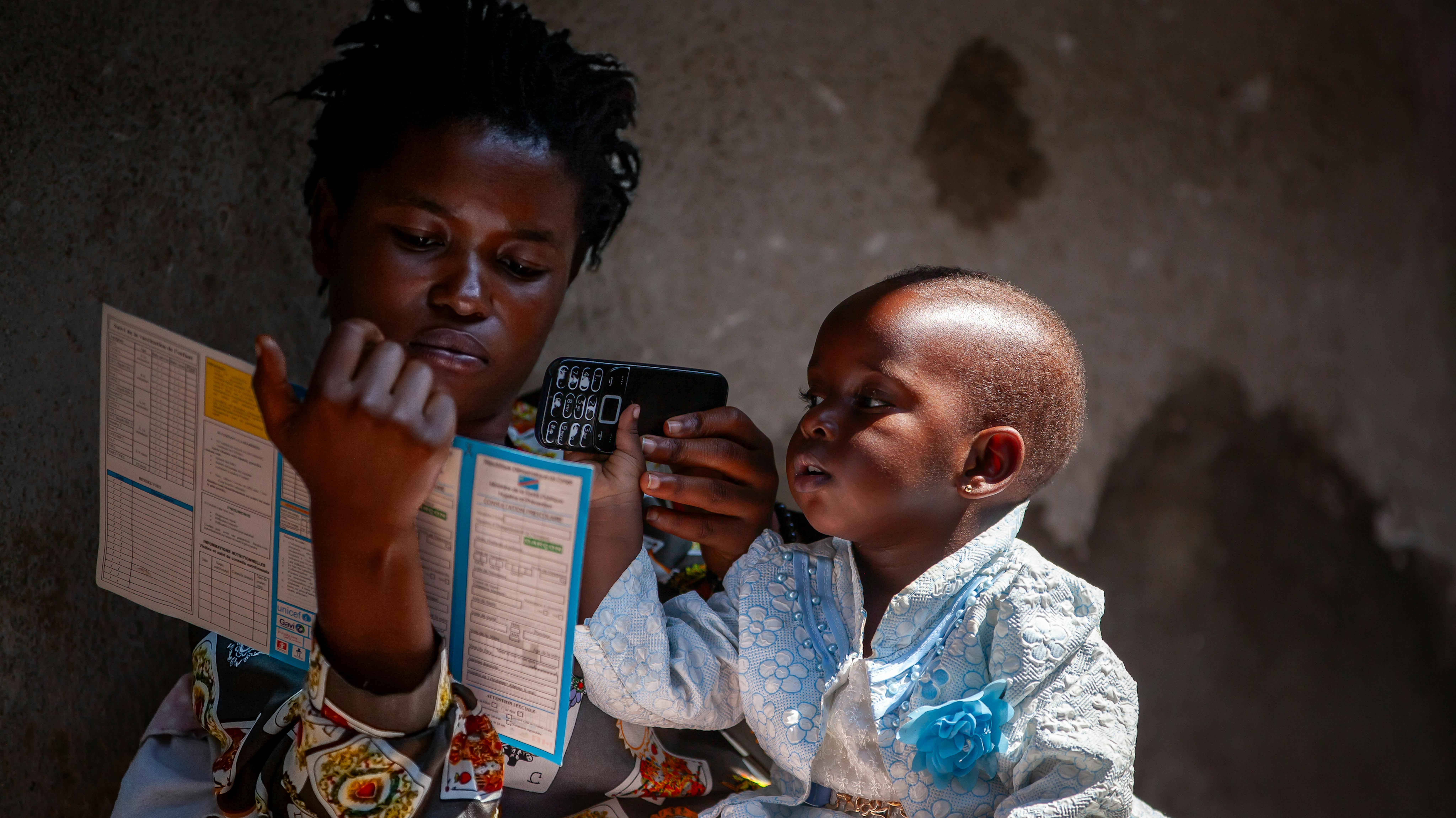 Una madre guarda il libretto delle vaccinazioni del suo bambino nel centro sanitario sulle alture di Minova, nella provincia del Sud Kivu