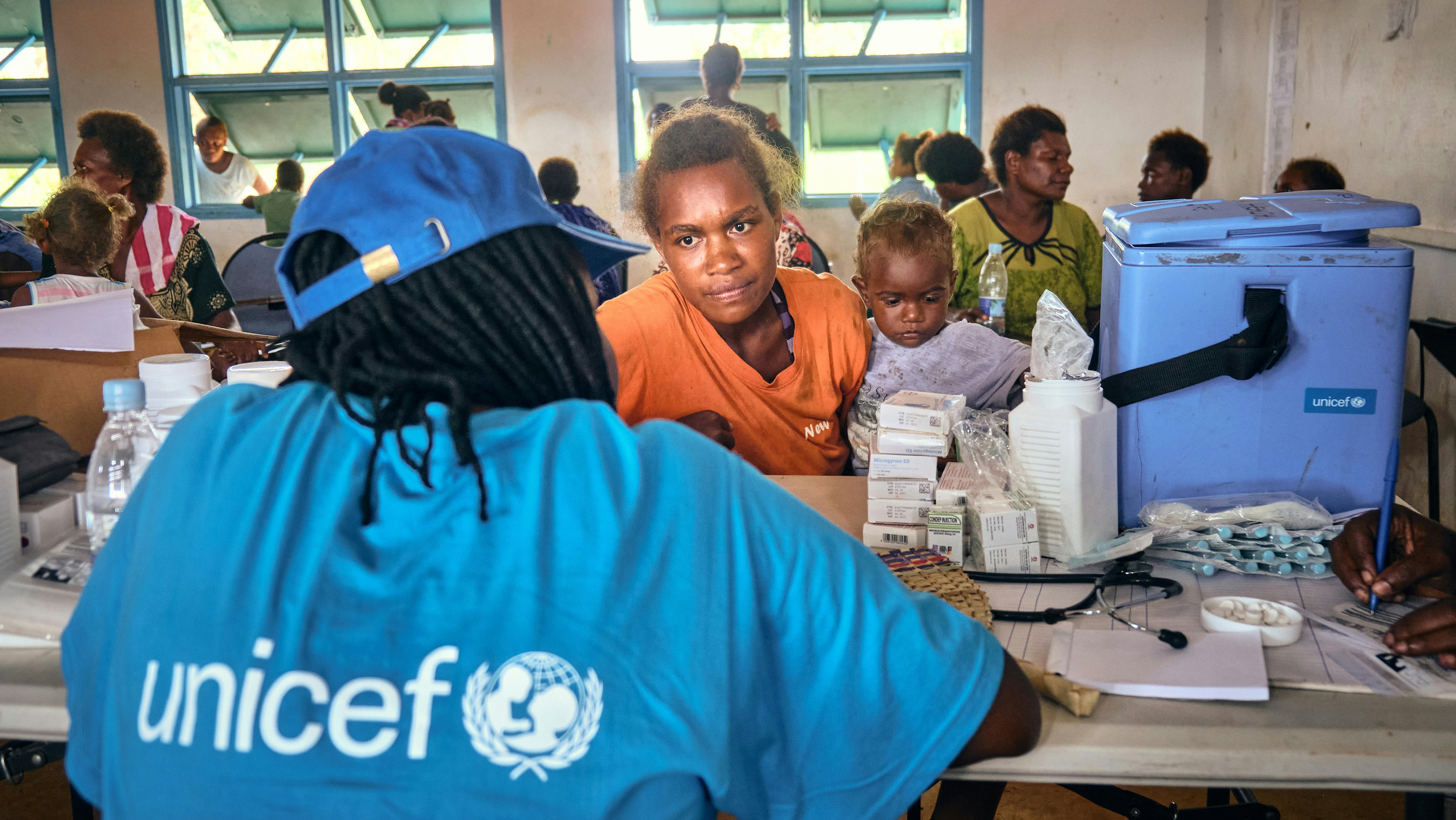 Vanuatu, Esaù, 11 mesi, si siede sulle ginocchia di sua madre mentre lei parla con un membro dello staff dell'UNICEF prima di vaccinarlo.