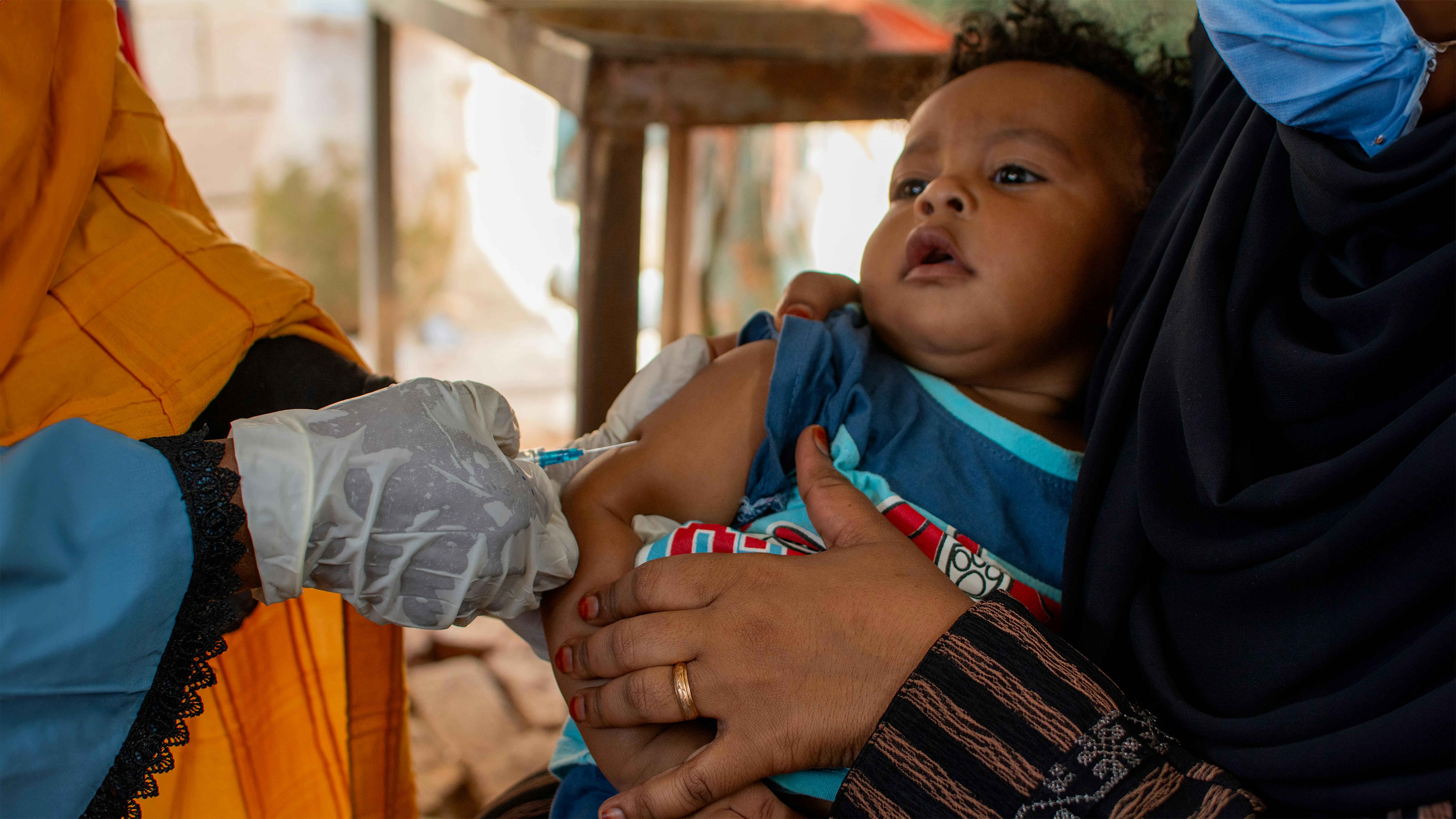 Sudan - Un bambino di nove mesi con la madre presso la struttura sanitaria di Hayal Arab, ad Atbara, nello stato del fiume Nilo, per ricevere vaccini salvavita come quello contro il morbillo.