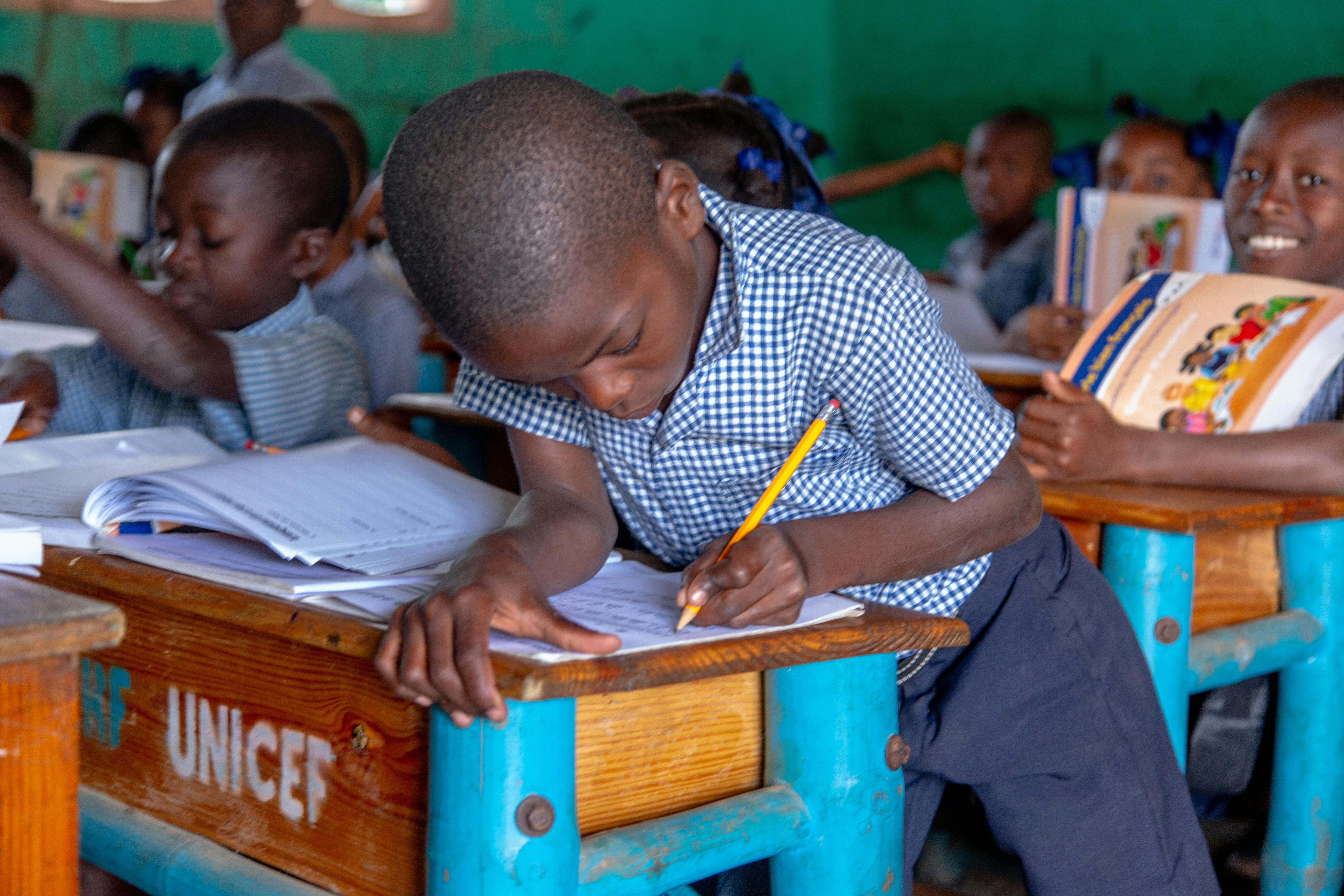 Nella scuola Dame Marie un bambino utilizza i materiali distribuiti dall'UNICEF per le lezioni