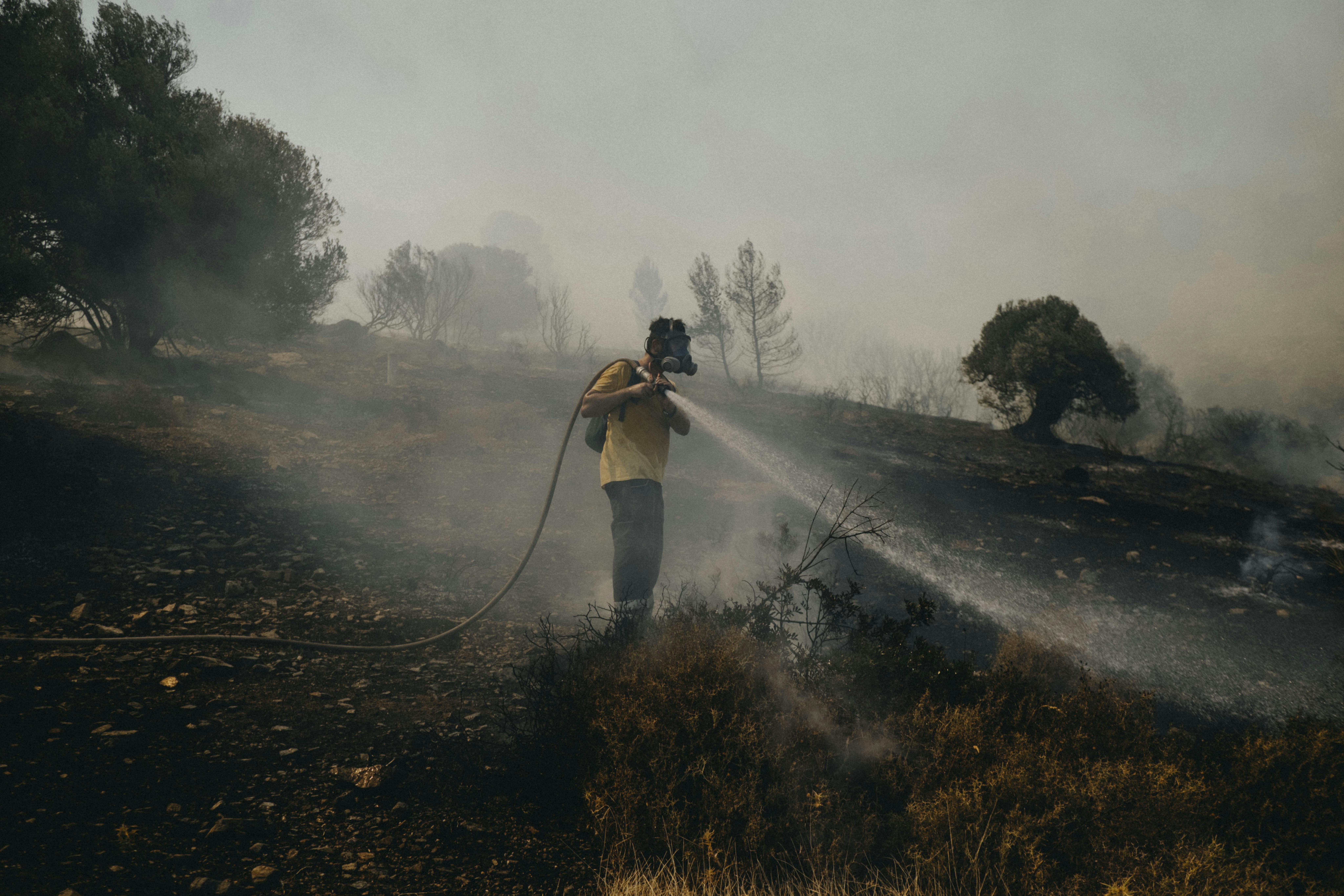 Un pompiere volontario aiuta a spegnere un incendio nella zona di Plaka, a Keratea, 40 km a sud-est di Atene