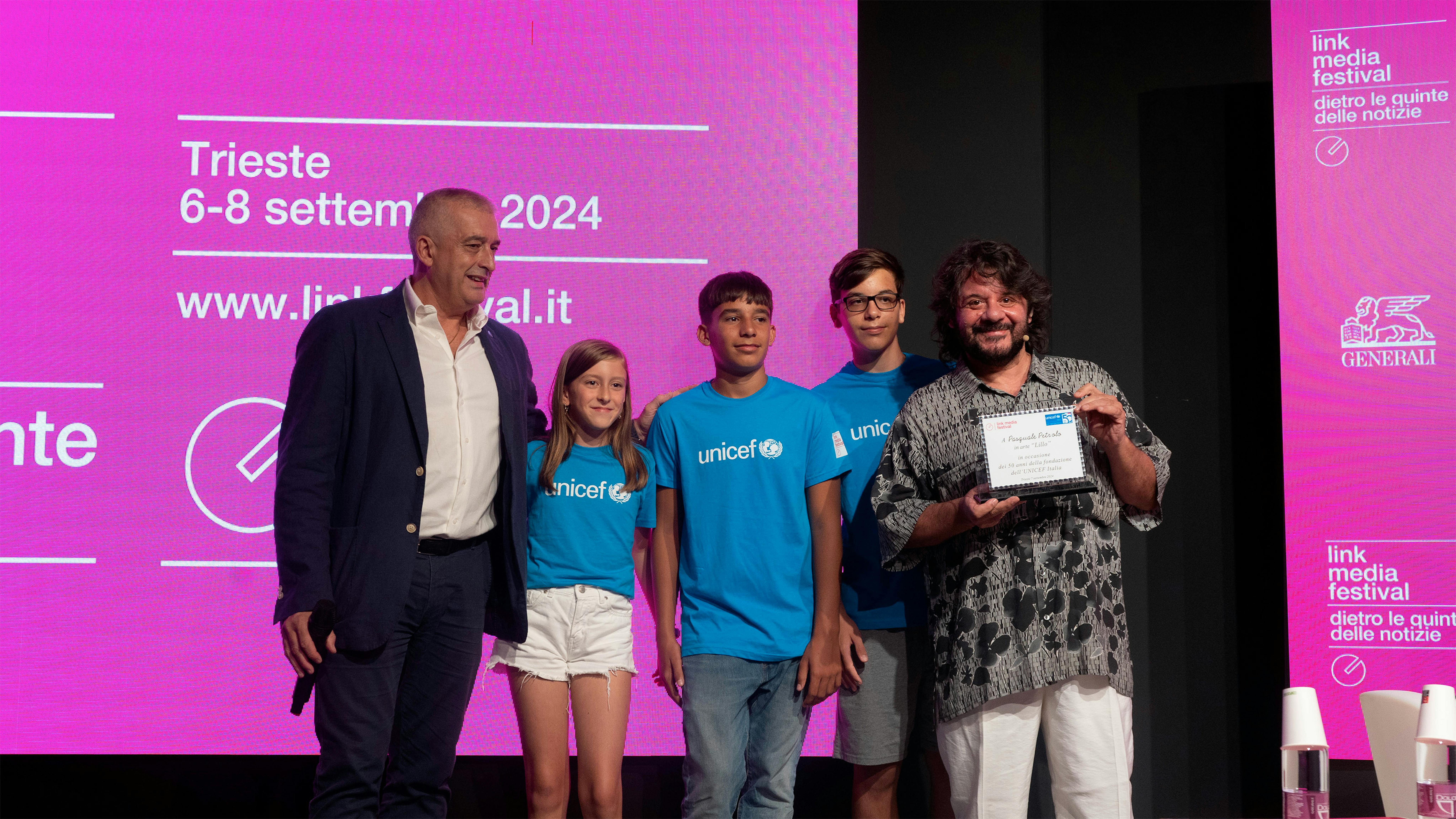 Paolo Rozera premia Lillo, alla presenza di alcuni bambini che indossano la maglietta dell'UNICEF.