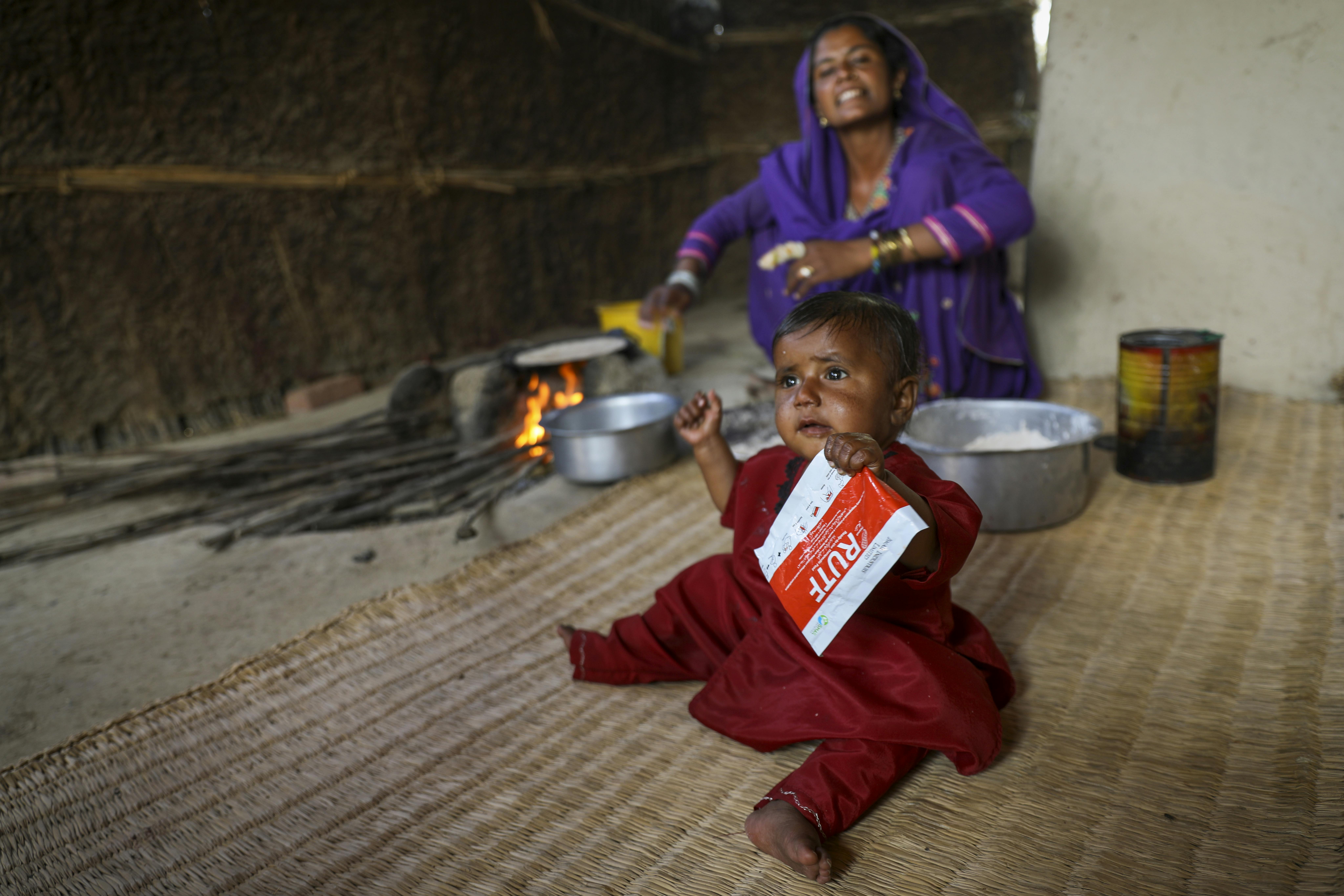 Pakistan: Farzana guarda sua figlia Shabira mentre assume il RUTF. Durante uno screening medico, sei mesi fa, alla bambina era stata diagnosticata la malnutrizione severa acuta. Dopo settimane di cure ora sta bene