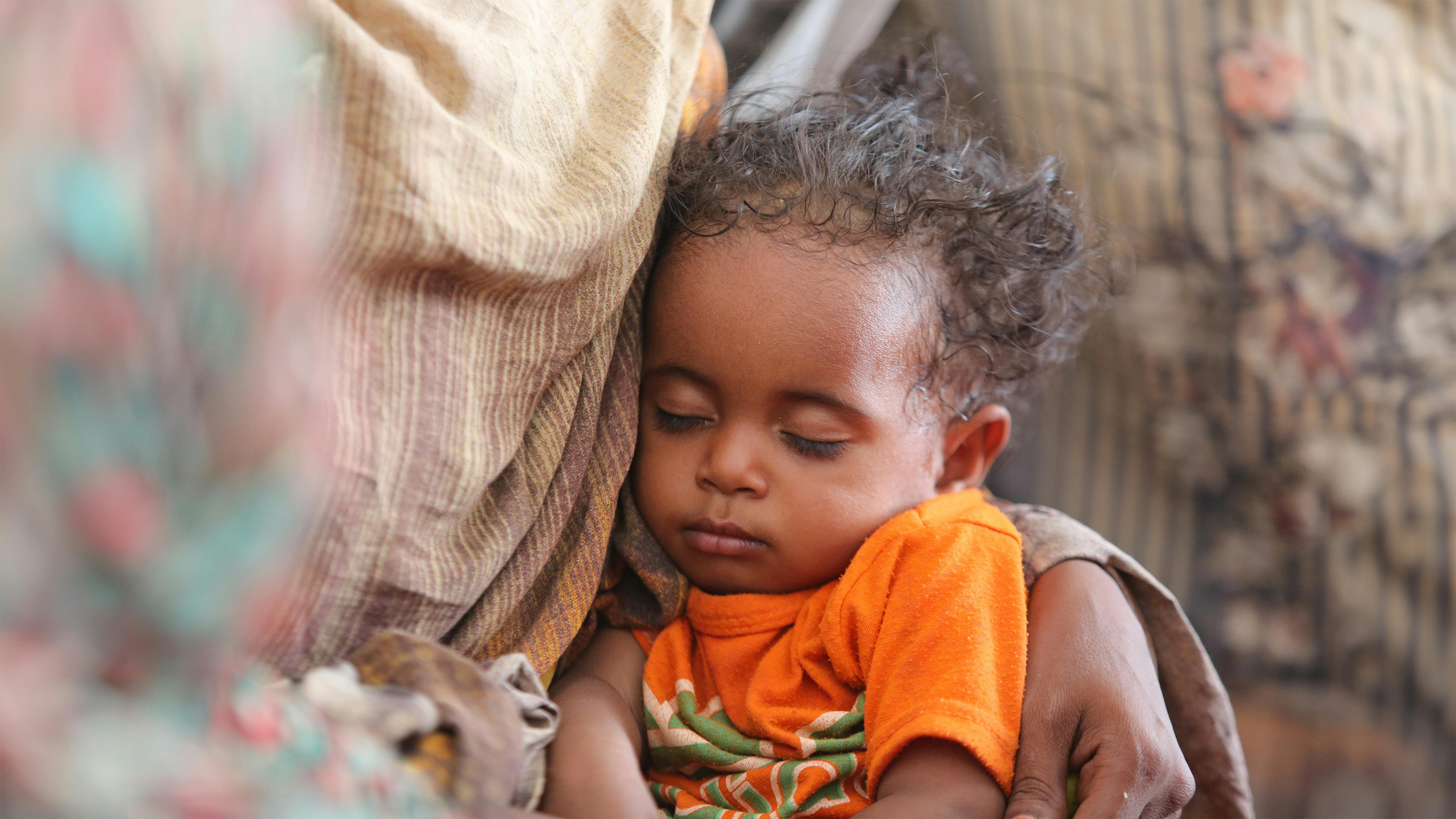 Sudan - un bambino dorme sulle ginocchia della madre ad Atbara