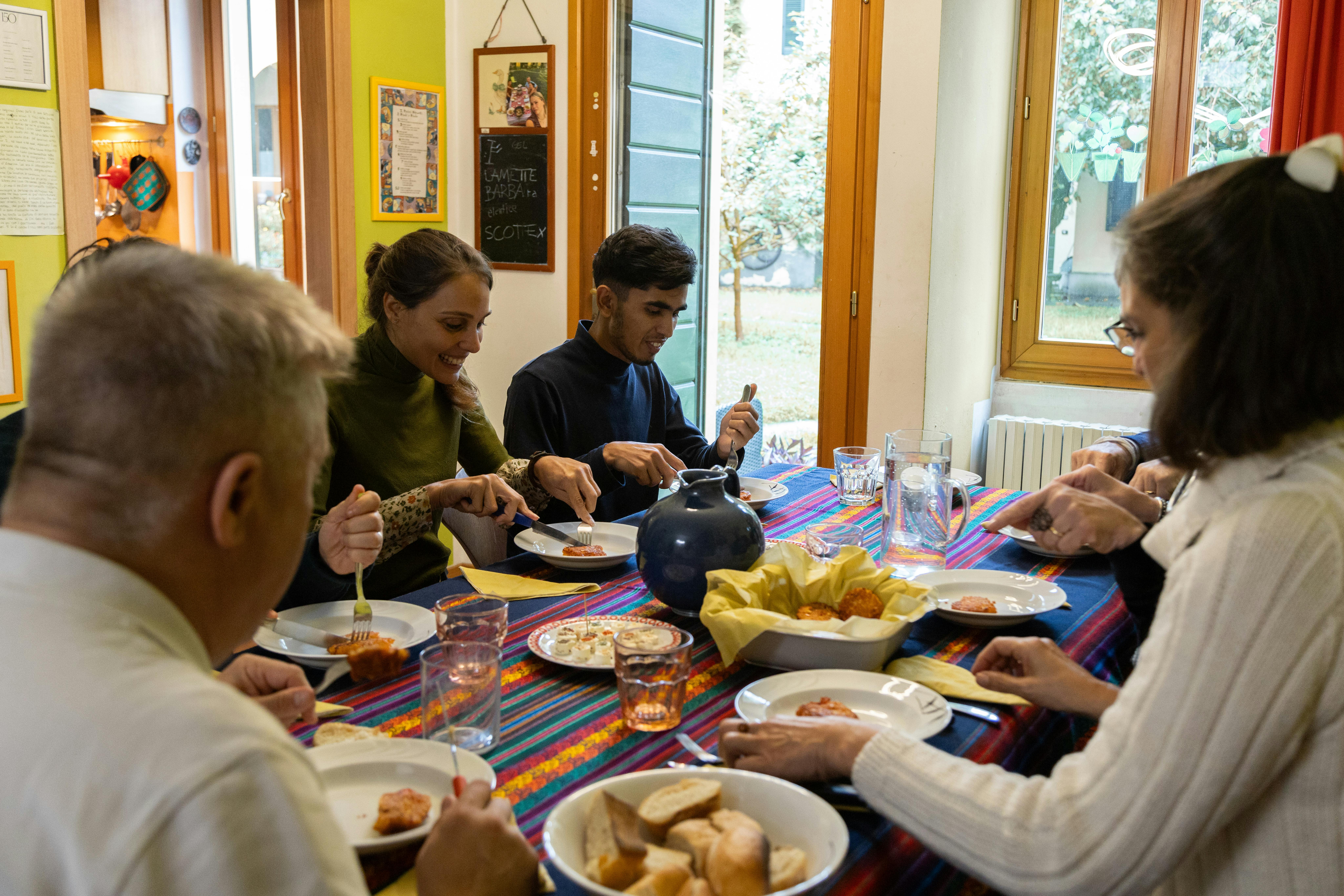 Nasim a tavola con la famiglia affidataria e operatrici e operatori UNICEF e CNCA