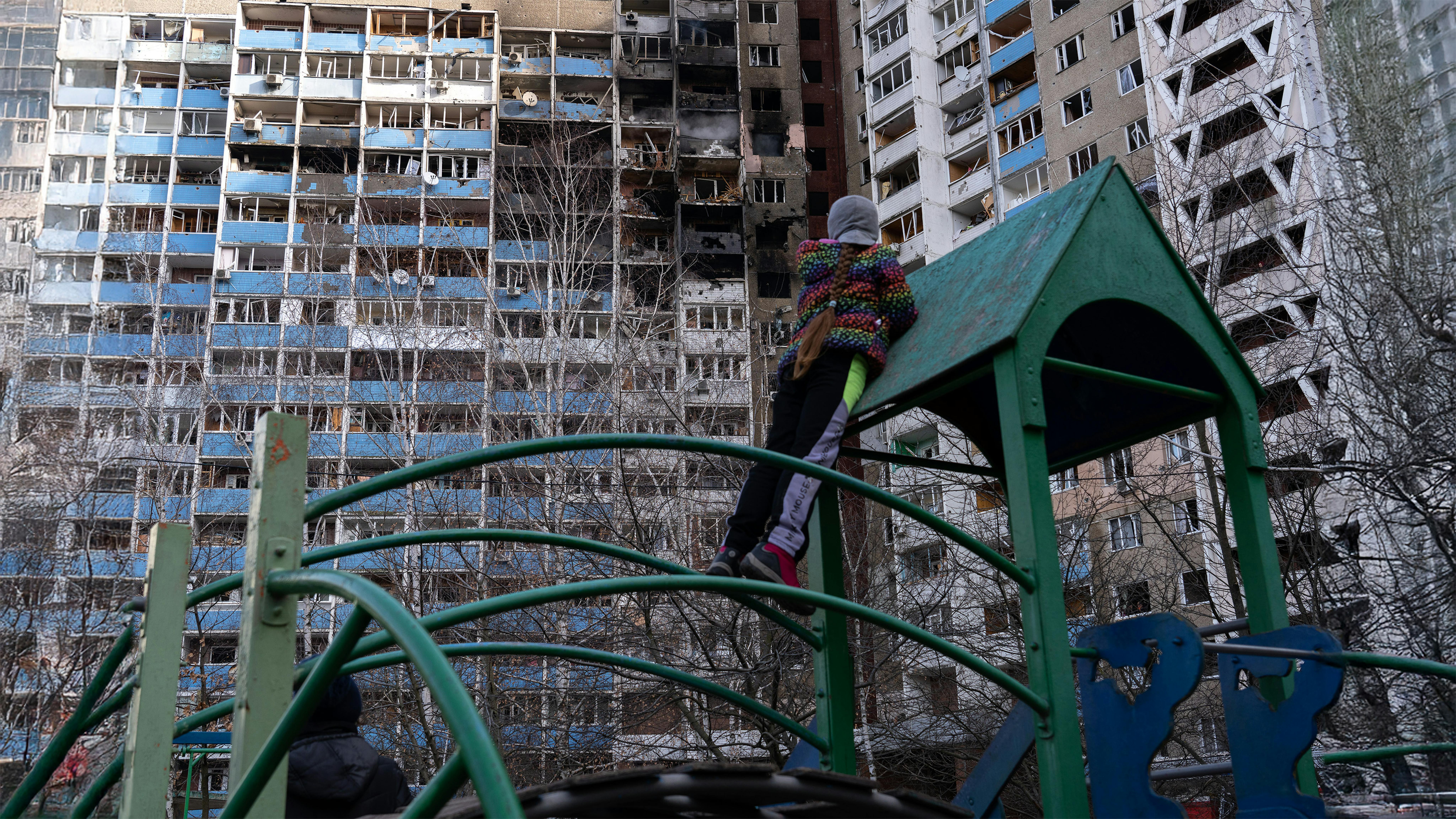 Una bambina  osserva gli appartamenti bruciati, in piedi nel parco giochi nel cortile del condominio, che ha subito i bombardamenti la mattina del 7 febbraio 2024, Kiev, Ucraina.