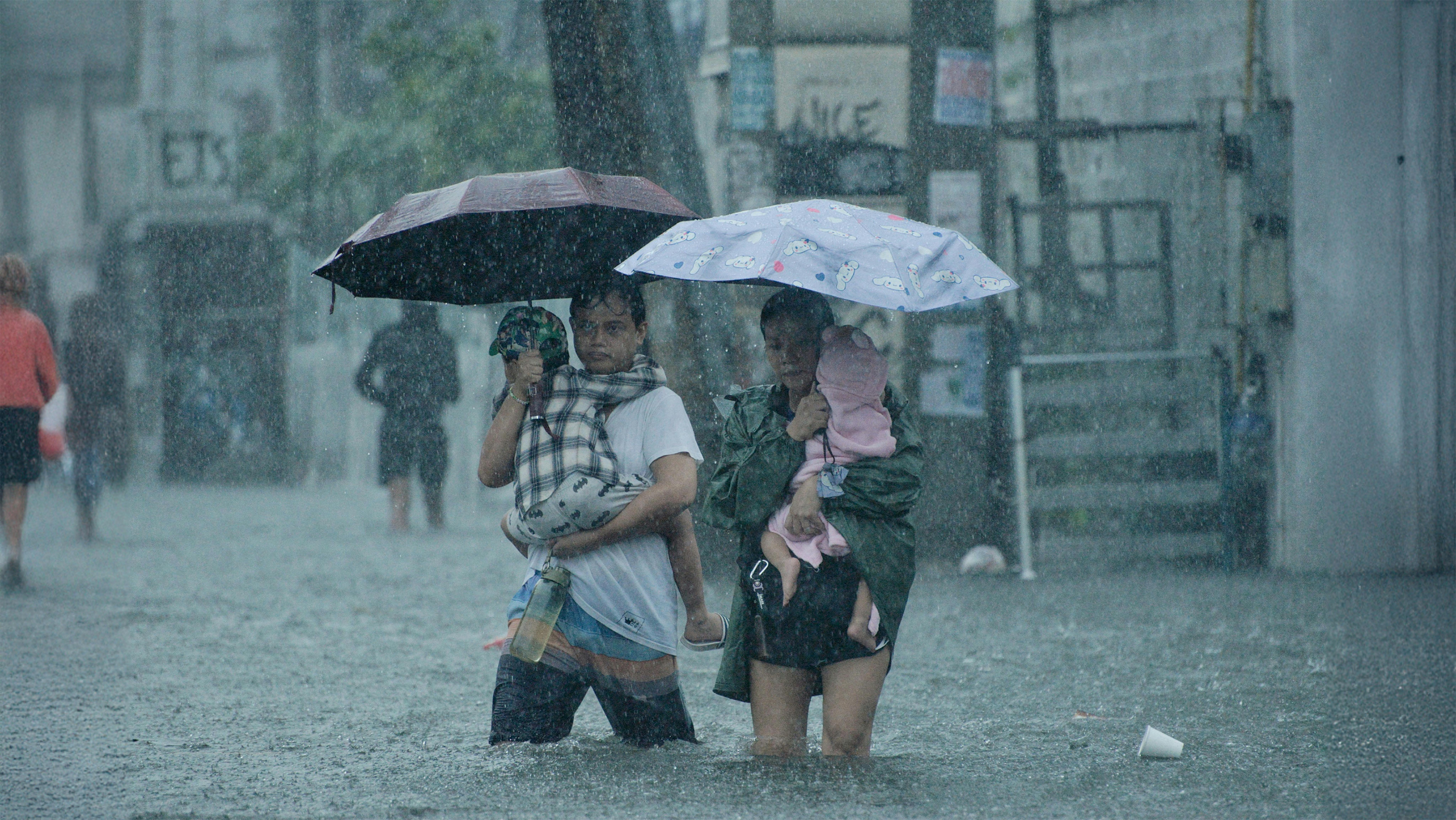 Filippine - Rogelio e la sua compagna Joan portano in braccio i loro figli mentre camminano su una strada allagata a Tatalon, Quezon City