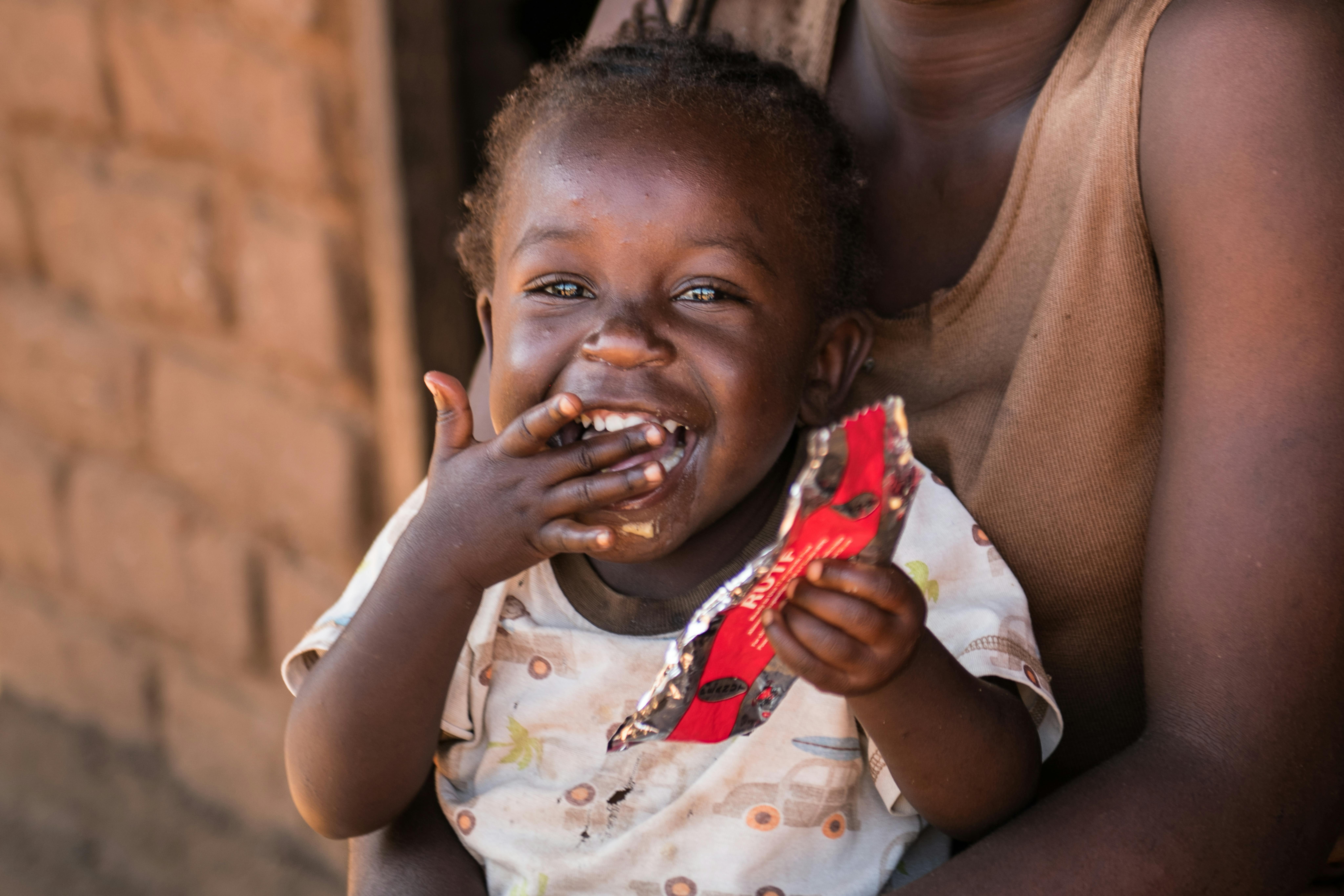 Malawi,  la piccola Christina Cosmas di 4 mesi si sta nutrendo con una bustina di  RUTF per riprendersi dalla malnutrizione