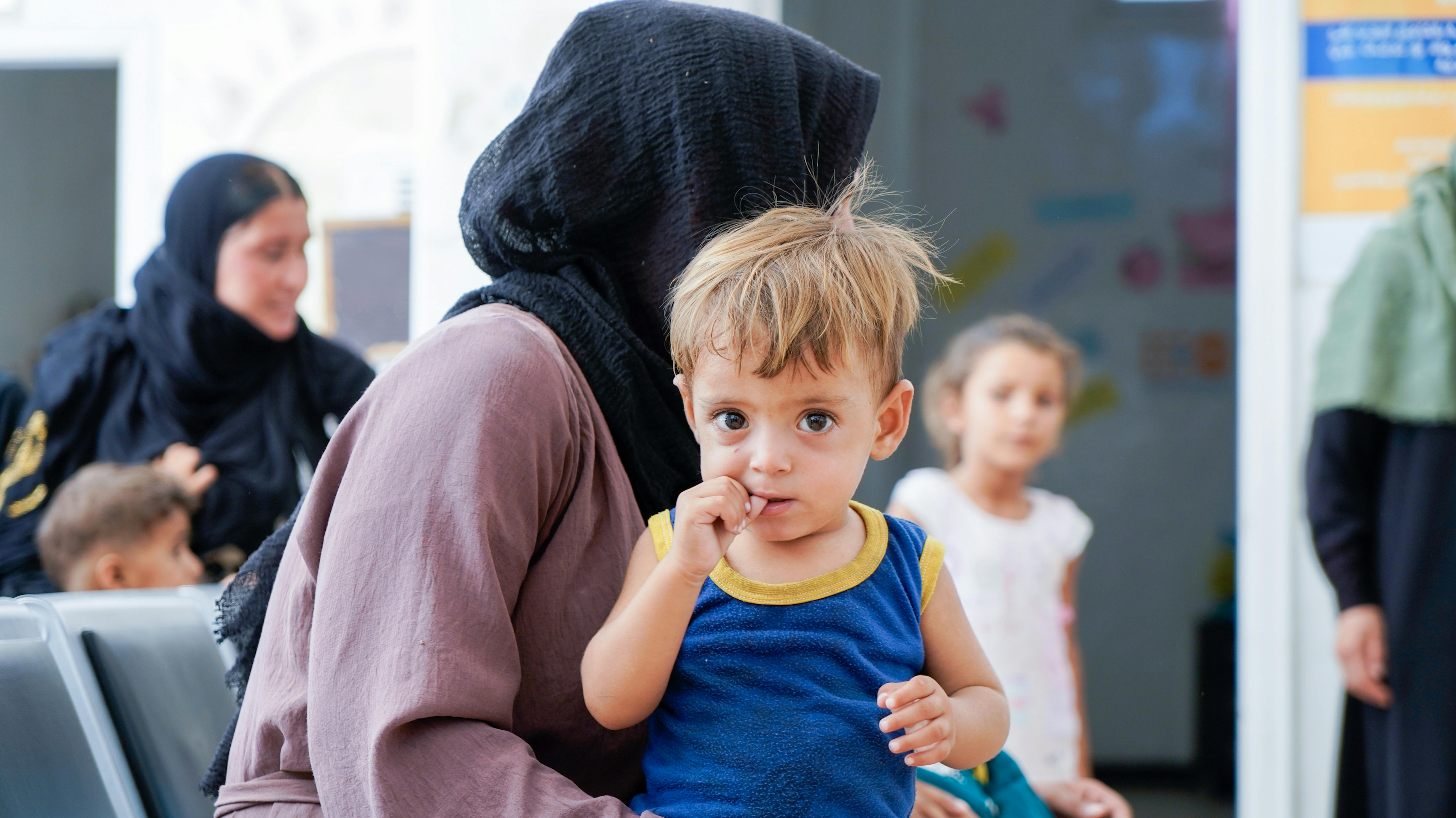 Nayla, 36 anni, con suo figlio Saif, 1,8 anni, in attesa in una clinica supportata dall'UNICEF nella città di Al-Hasakeh, in Siria