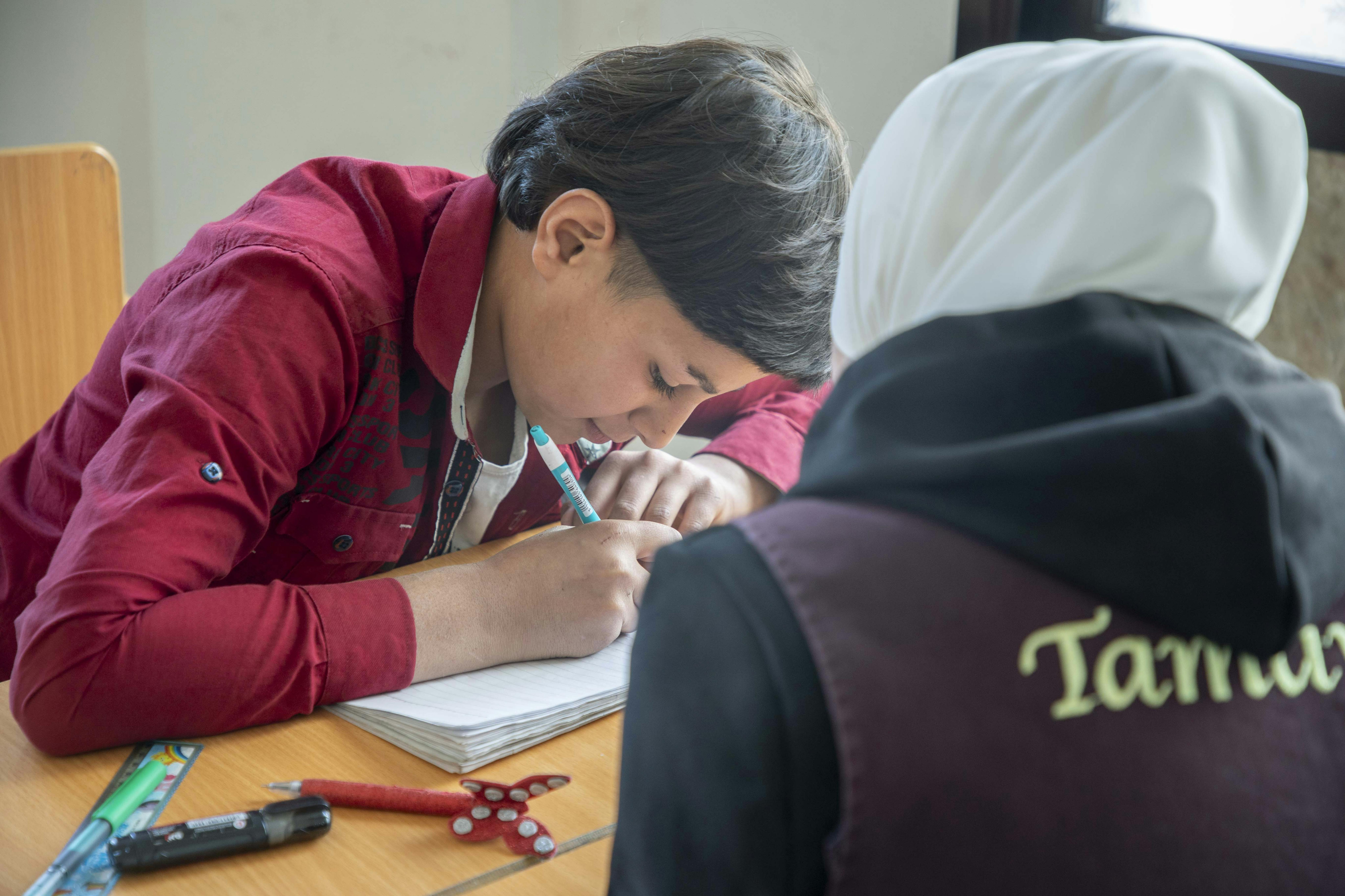 Yousef, 13 anni, scrive durante la sua sessione individuale con il suo insegnante in un centro di autoapprendimento supportato dall'UNICEF nella città di Saqba, Damasco rurale, Siria, 6 novembre 2024.