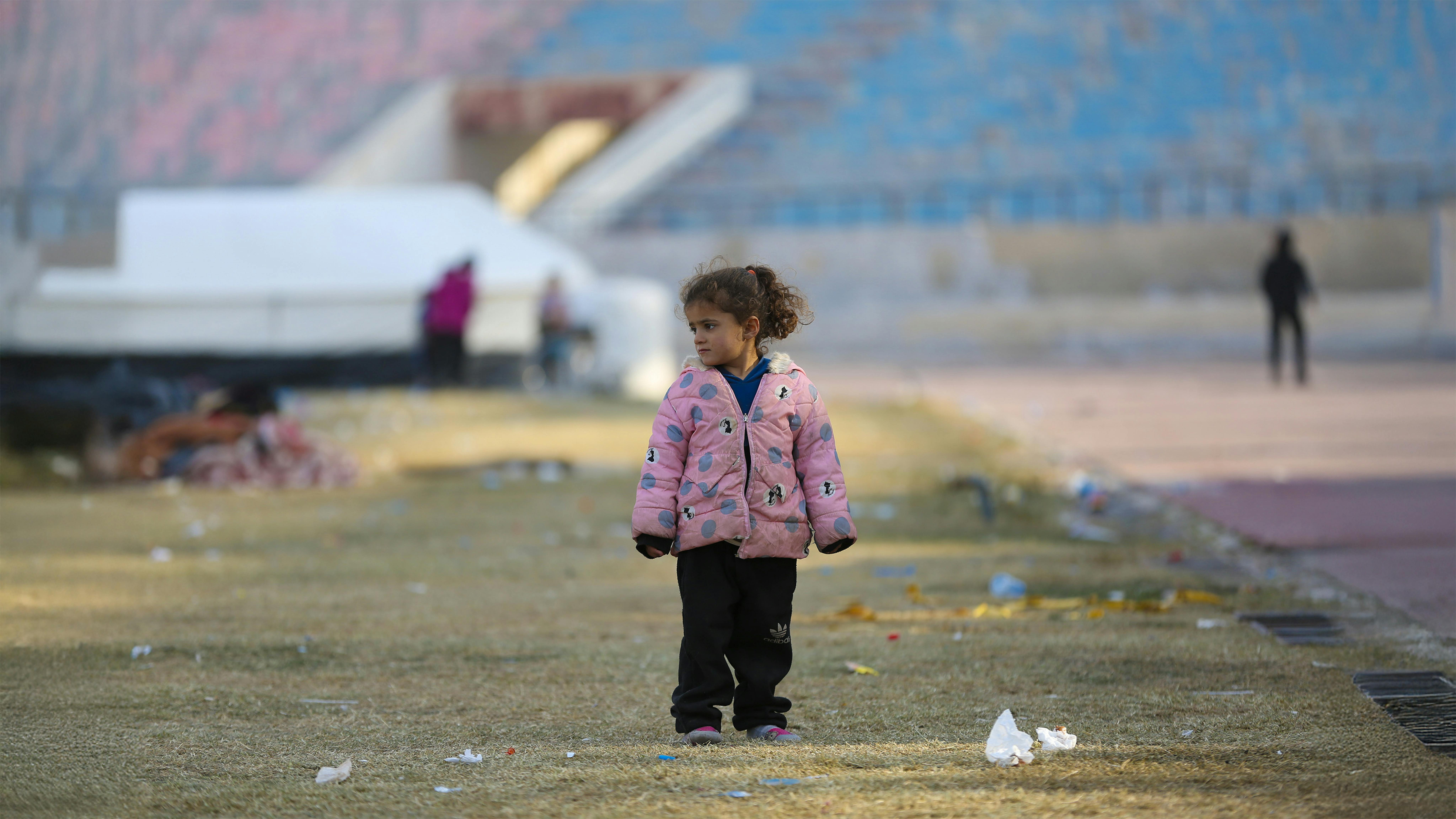 Una bambina in piedi al freddo.  Fa parte della famiglia appena arrivata in un centro di accoglienza nella città di Ar-Raqqa, in Siria, il 4 dicembre 2024, fuggita dall'escalation di violenza ad Aleppo