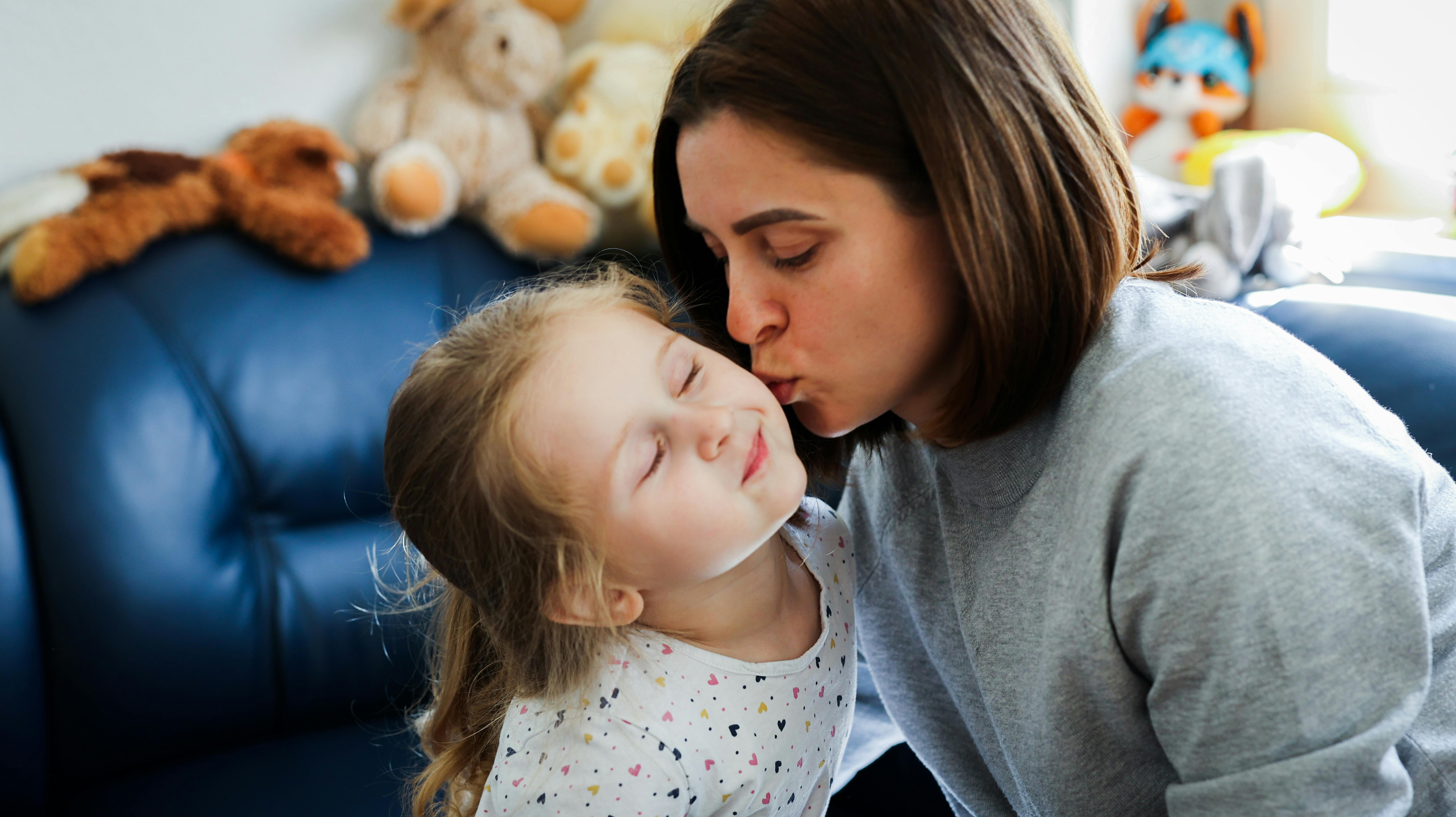 Una mamma bacia sulla guancia la sua bambina