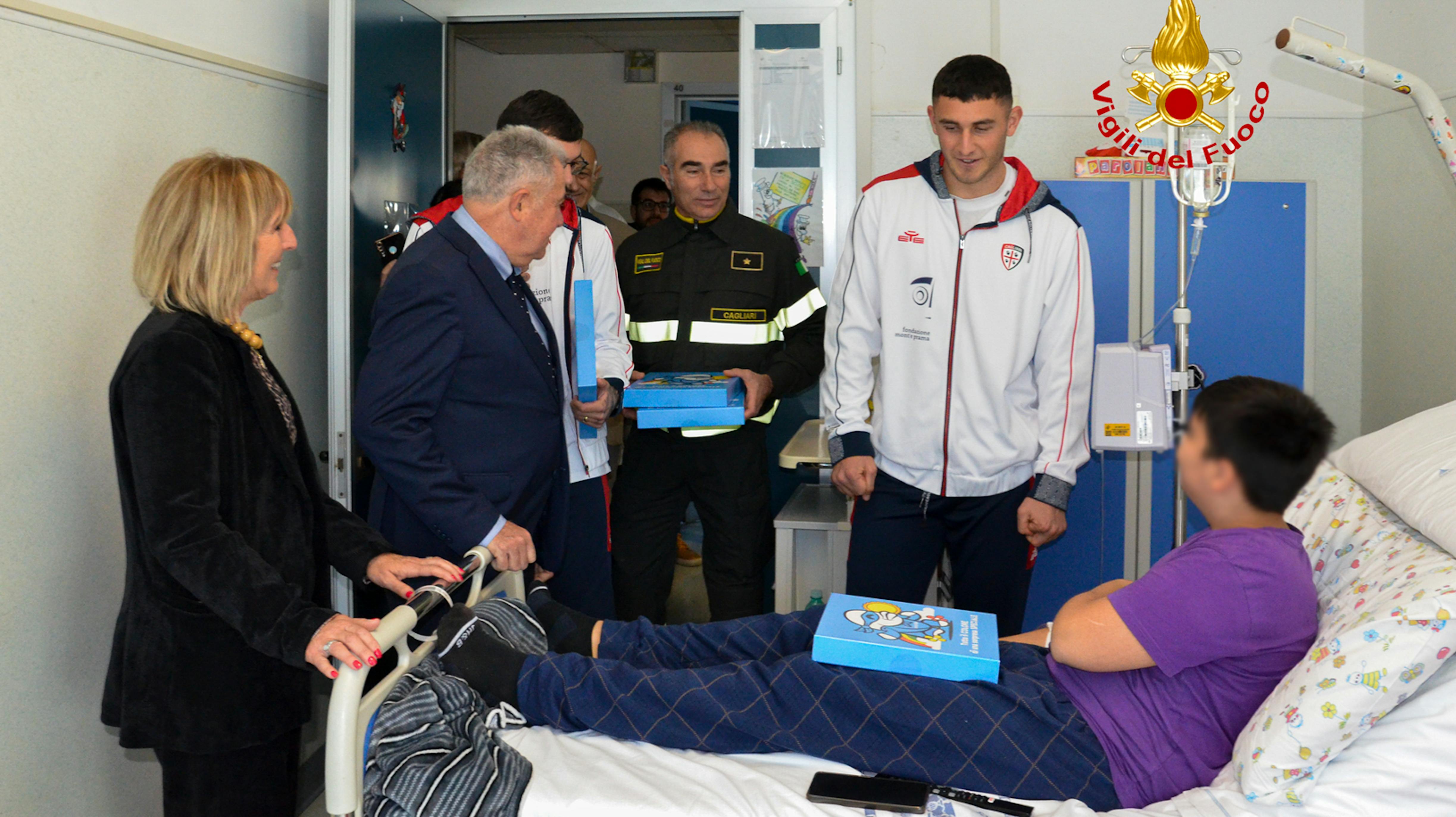I giocatori de Cagliari e i Vigili del fuoco nell'ospedale ARNAS G.Brotzu  di Cagliari consegnano il regalo sospeso a un bambino ricoverato