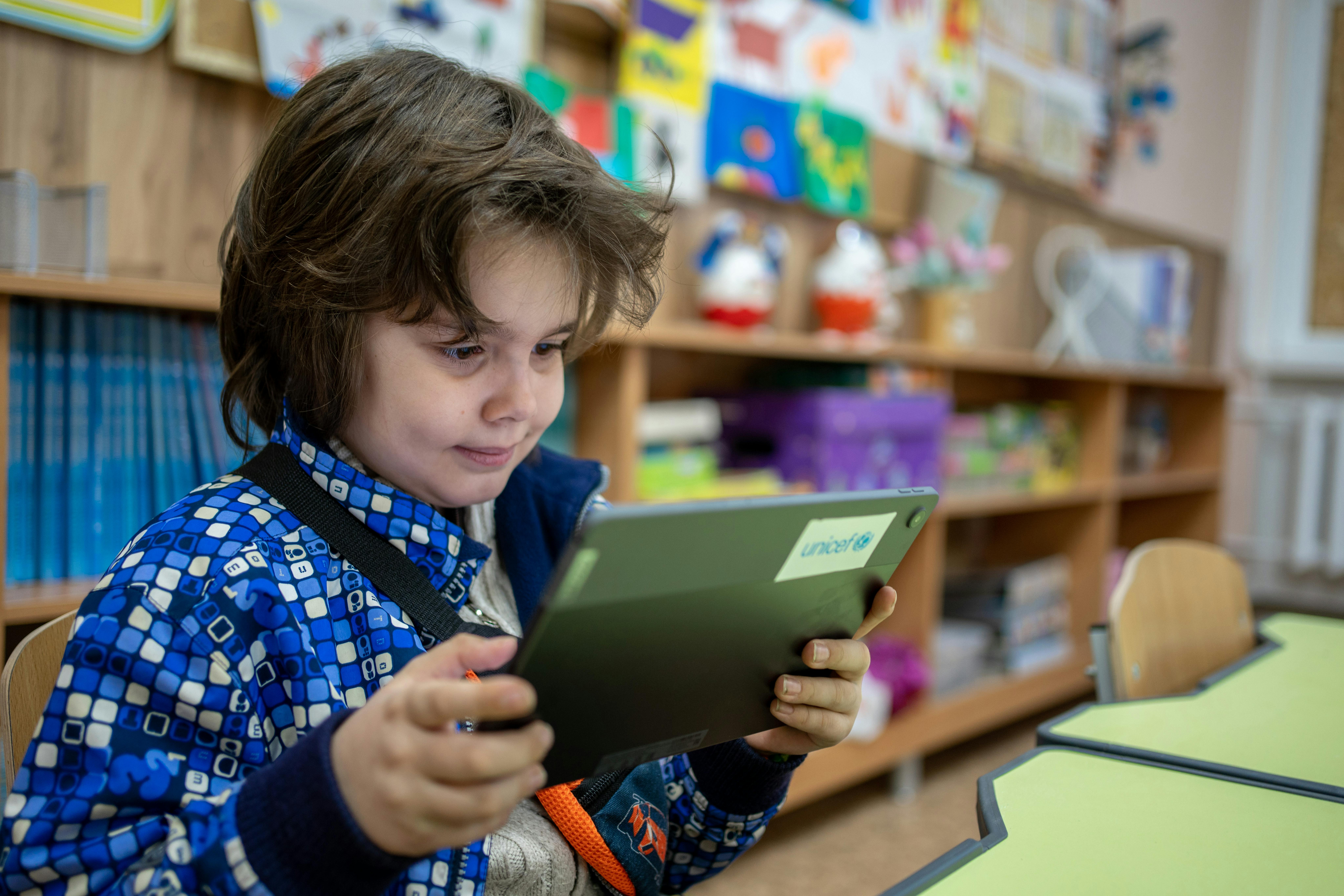 Bambino utilizza un tablet con logo UNICEF