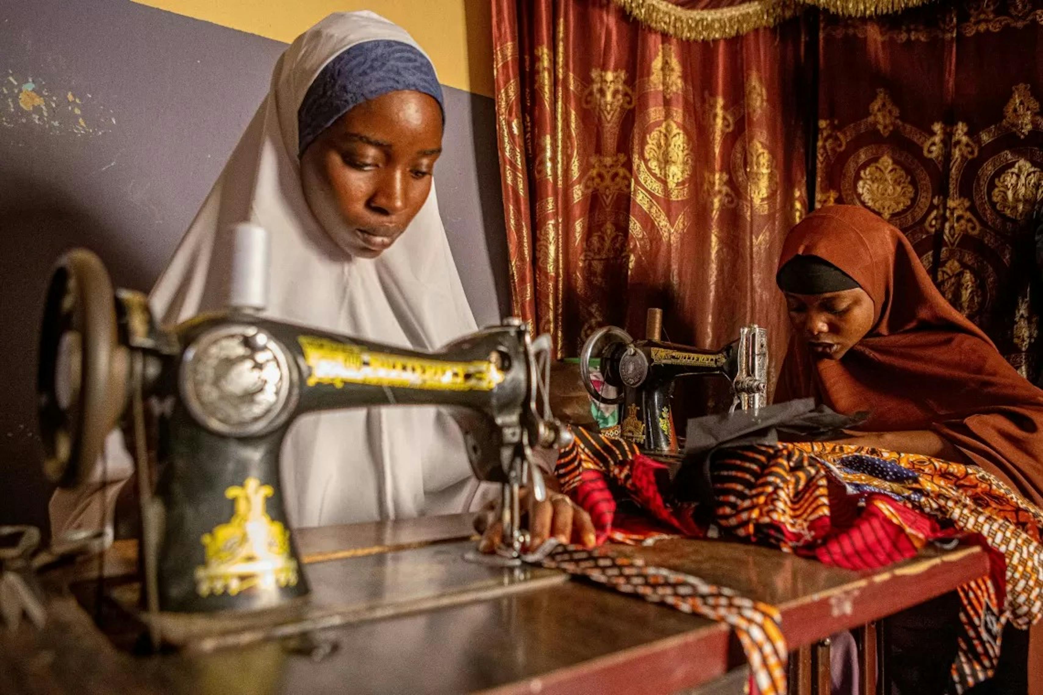 Rufaida è a casa nella città di Zaria, Stato di Kaduna, Nigeria e lavora con la sua migliore amica Raliya, anche lei apprendista sarta.