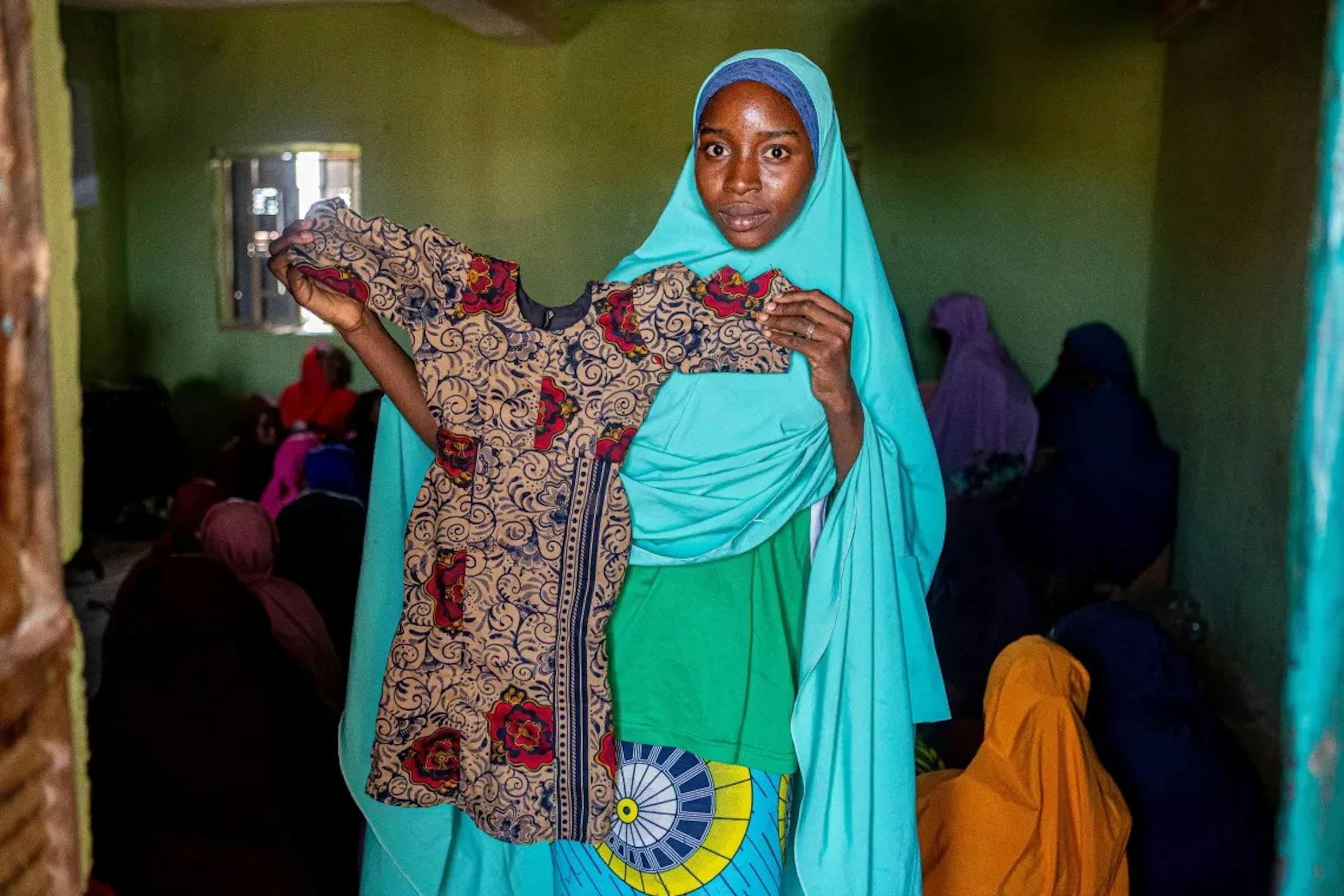 Raliya mostra il vestito che ha realizzato. Siamo a Zaria, Stato di Kaduna, Nigeria.